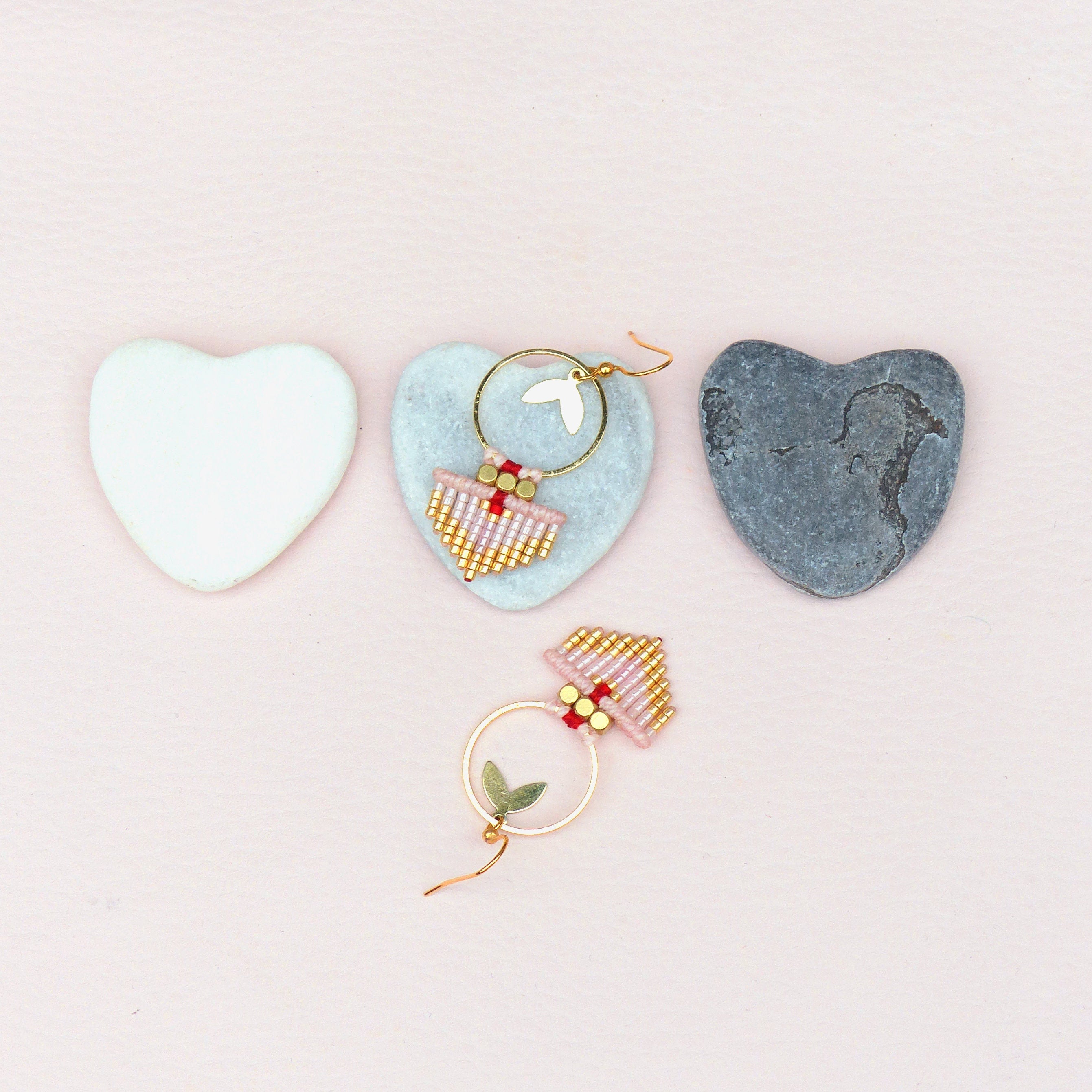 Peut inclure: Deux paires de boucles d'oreilles en perles roses et dorées avec un design en frange. Une paire a un petit anneau en or et l'autre a un anneau en or plus grand avec un motif de feuille.