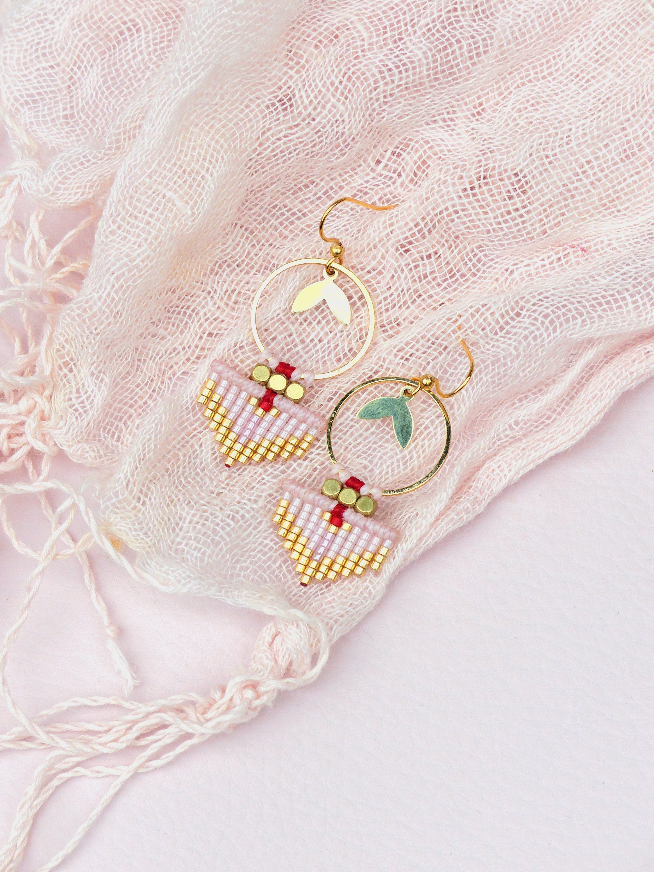 Peut inclure: Une paire de boucles d'oreilles en or avec des formes de goutte en perles roses et rouges et des cercles en or avec des accents de feuilles.