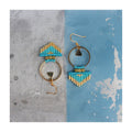Peut inclure: Une paire de boucles d'oreilles créoles dorées avec des franges de perles turquoise et dorées et un charme triangle doré.