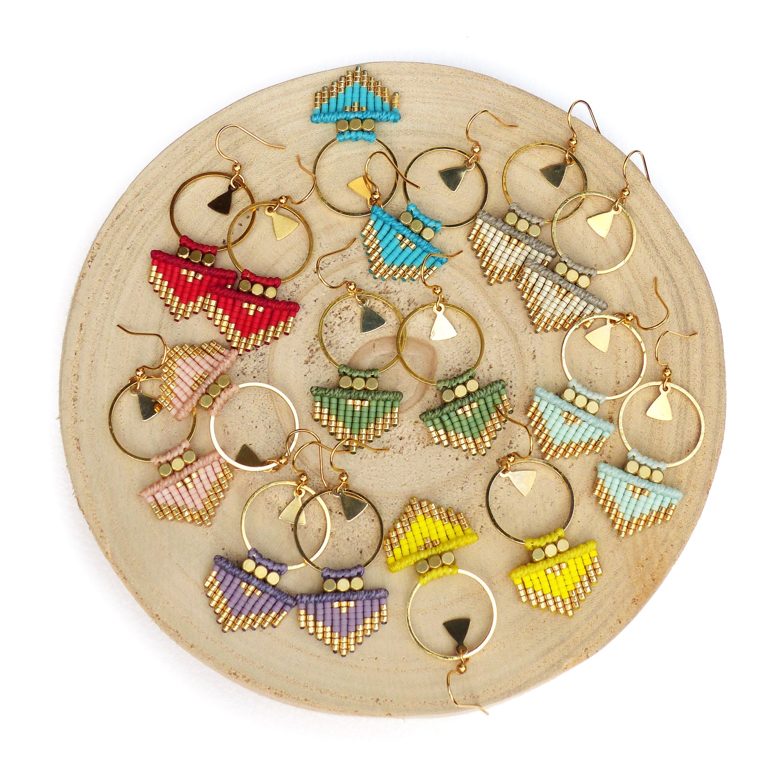 Peut inclure: Un ensemble de 10 paires de boucles d'oreilles en perles avec des cercles dorés et des franges. Les boucles d'oreilles sont de différentes couleurs, notamment rouge, bleu, vert, jaune et violet.