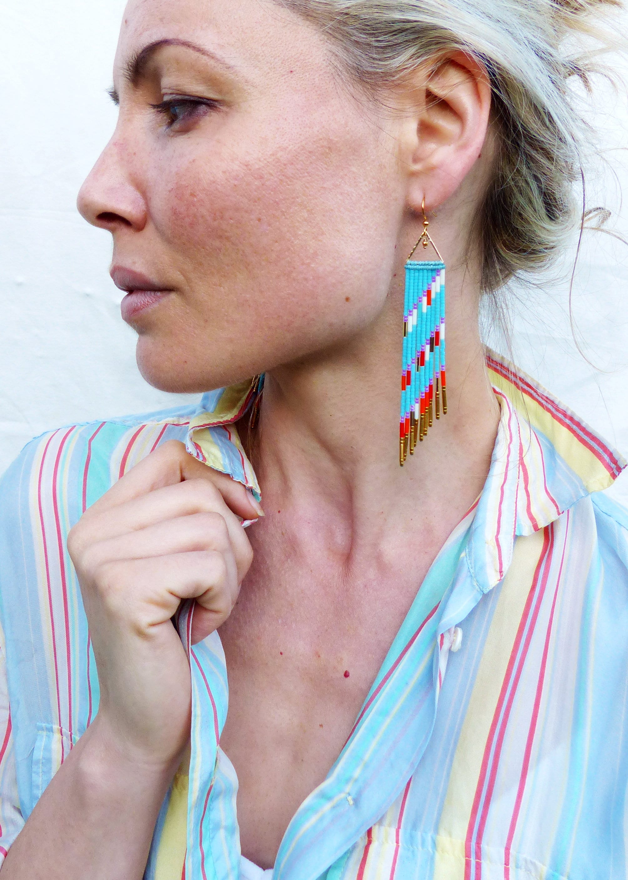 Peut inclure: Une femme portant une chemise rayée avec de longues boucles d'oreilles en perles turquoise, rouge, blanc et or.