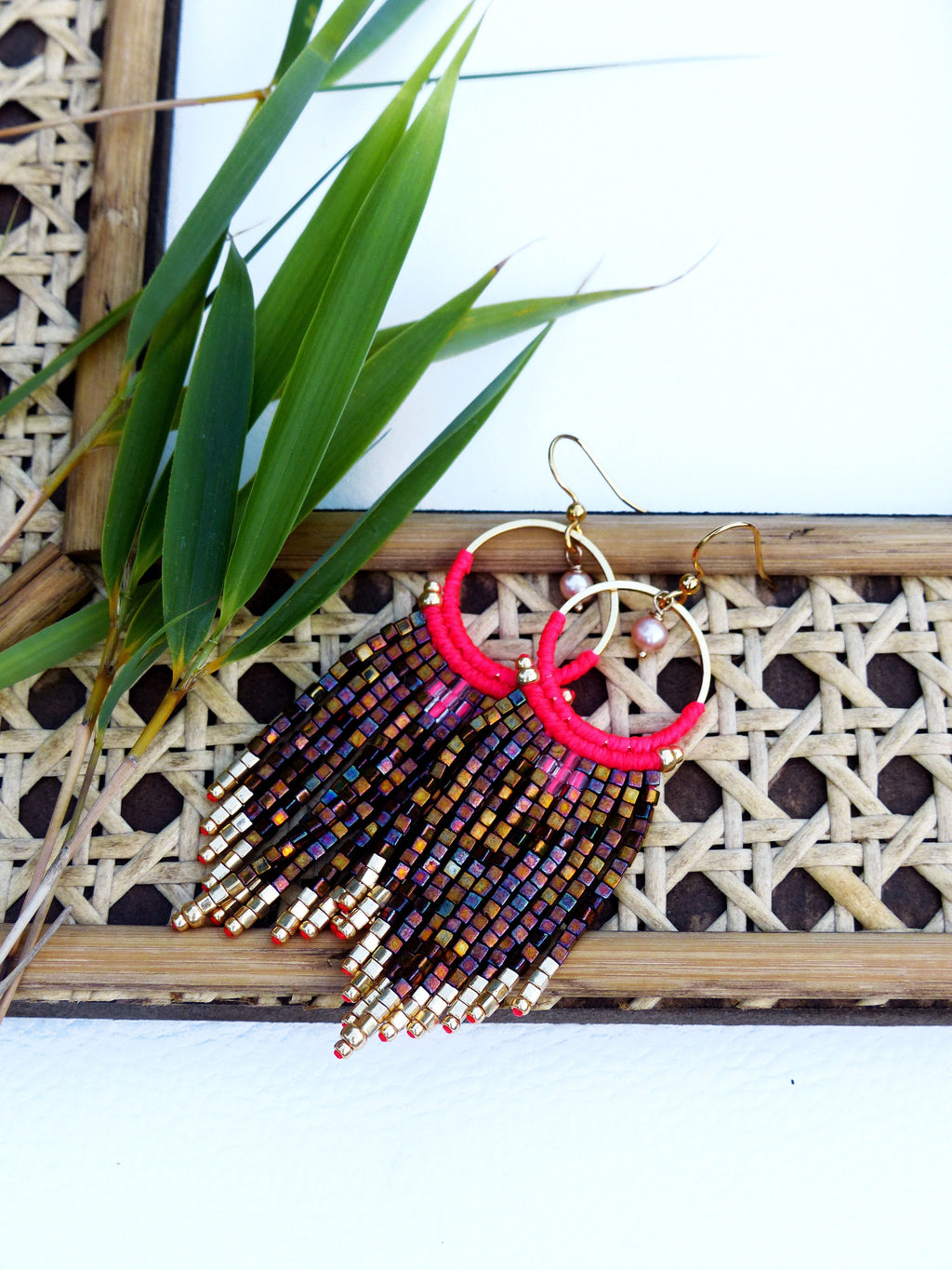 Peut inclure: Une paire de boucles d'oreilles créoles dorées avec un pendentif rose en perles brunes et dorées irisées.