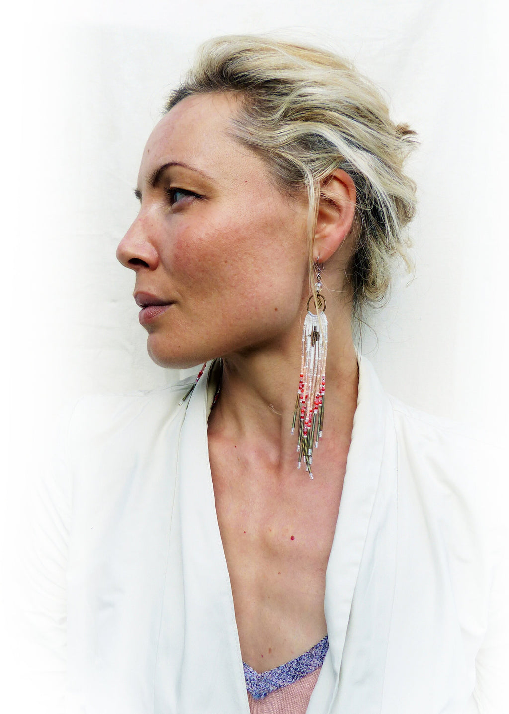 Peut inclure: Une femme portant une veste blanche avec de longues boucles d'oreilles en perles. Les boucles d'oreilles sont blanches, rouges et dorées avec un petit charme circulaire en haut.
