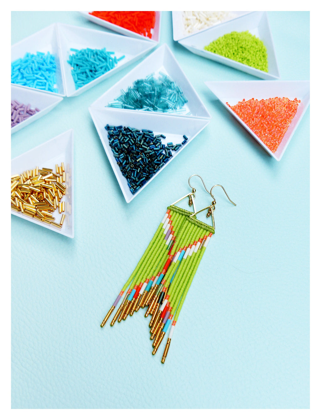 Peut inclure: Une paire de longues boucles d'oreilles en perles vertes avec des accents dorés. Les boucles d'oreilles sont faites avec une variété de perles colorées, y compris le blanc, le rouge et le bleu. Les boucles d'oreilles sont suspendues à des crochets dorés.