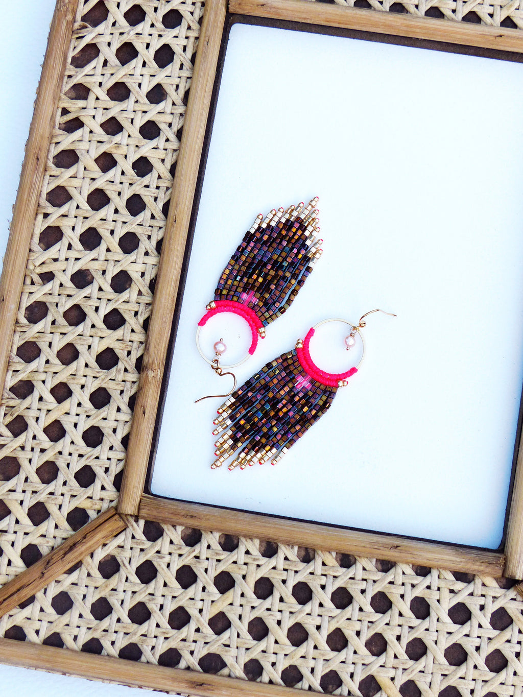 Peut inclure: Une paire de boucles d'oreilles en perles avec un motif rose et or. Les boucles d'oreilles sont suspendues à un cadre tissé.