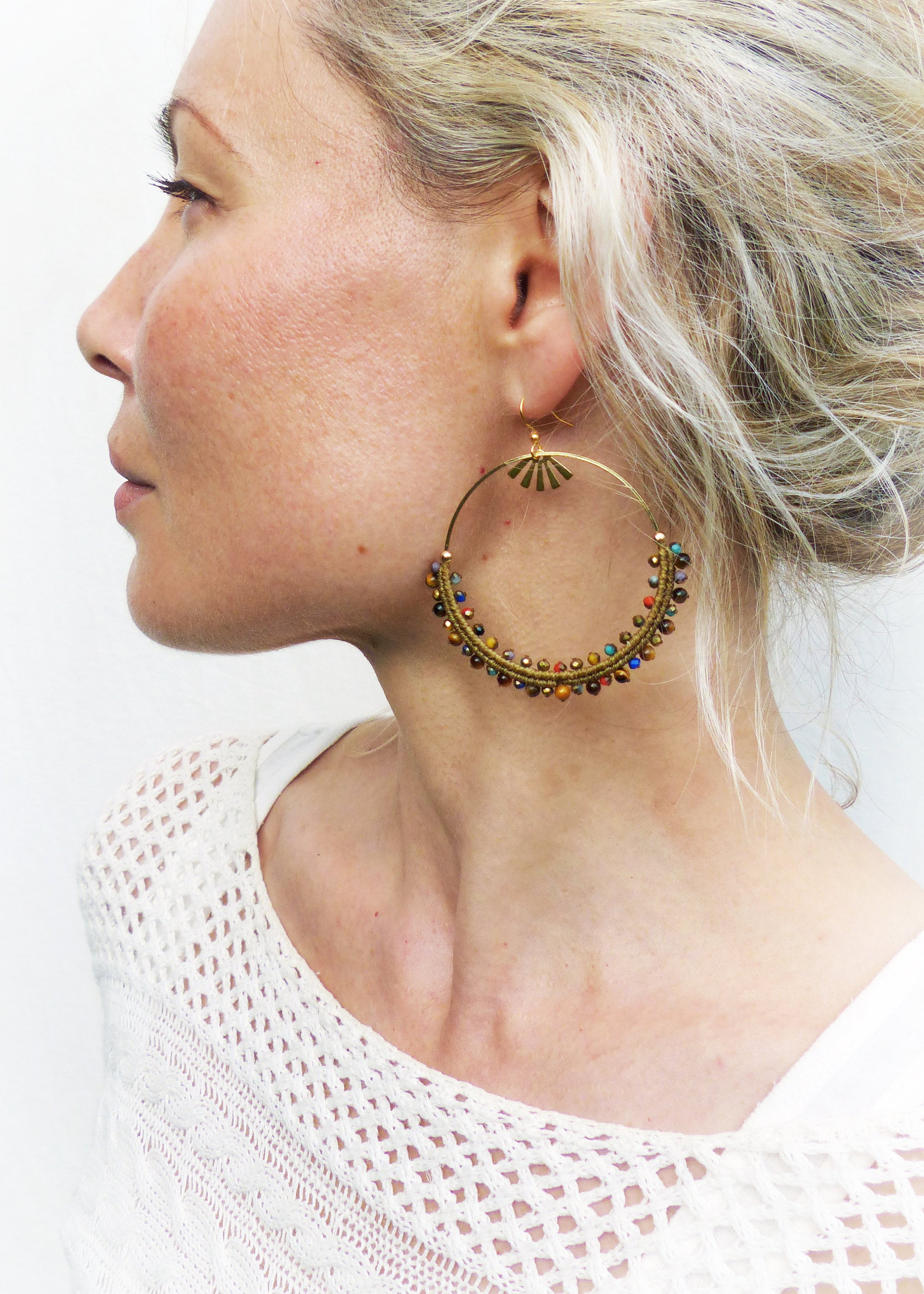 Peut inclure: Boucles d'oreilles créoles dorées avec un design perlé présentant une variété de couleurs, notamment le brun, l'or et le bleu.