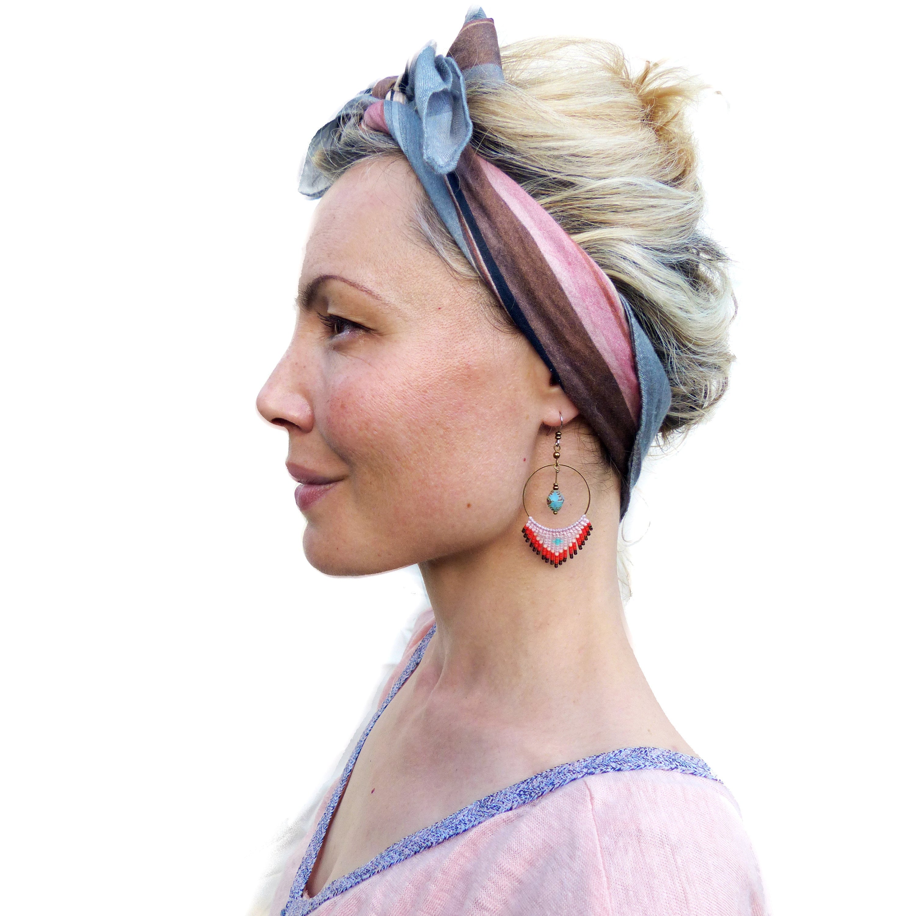 Peut inclure: Une femme aux cheveux blonds portant un bandana à motifs bleus et bruns et une paire de boucles d'oreilles pendantes avec des perles turquoise et rouges.
