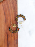 Peut inclure: Une paire de boucles d'oreilles créoles dorées avec un motif soleil et des perles multicolores. Les perles sont brunes, rouges, bleues, vertes et jaunes.