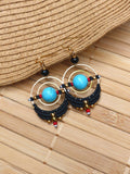 Peut inclure: Une paire de boucles d'oreilles créoles turquoise et noires avec des accents dorés. Les boucles d'oreilles présentent une pierre turquoise au centre de chaque créole, entourée de perles noires et d'accents dorés.