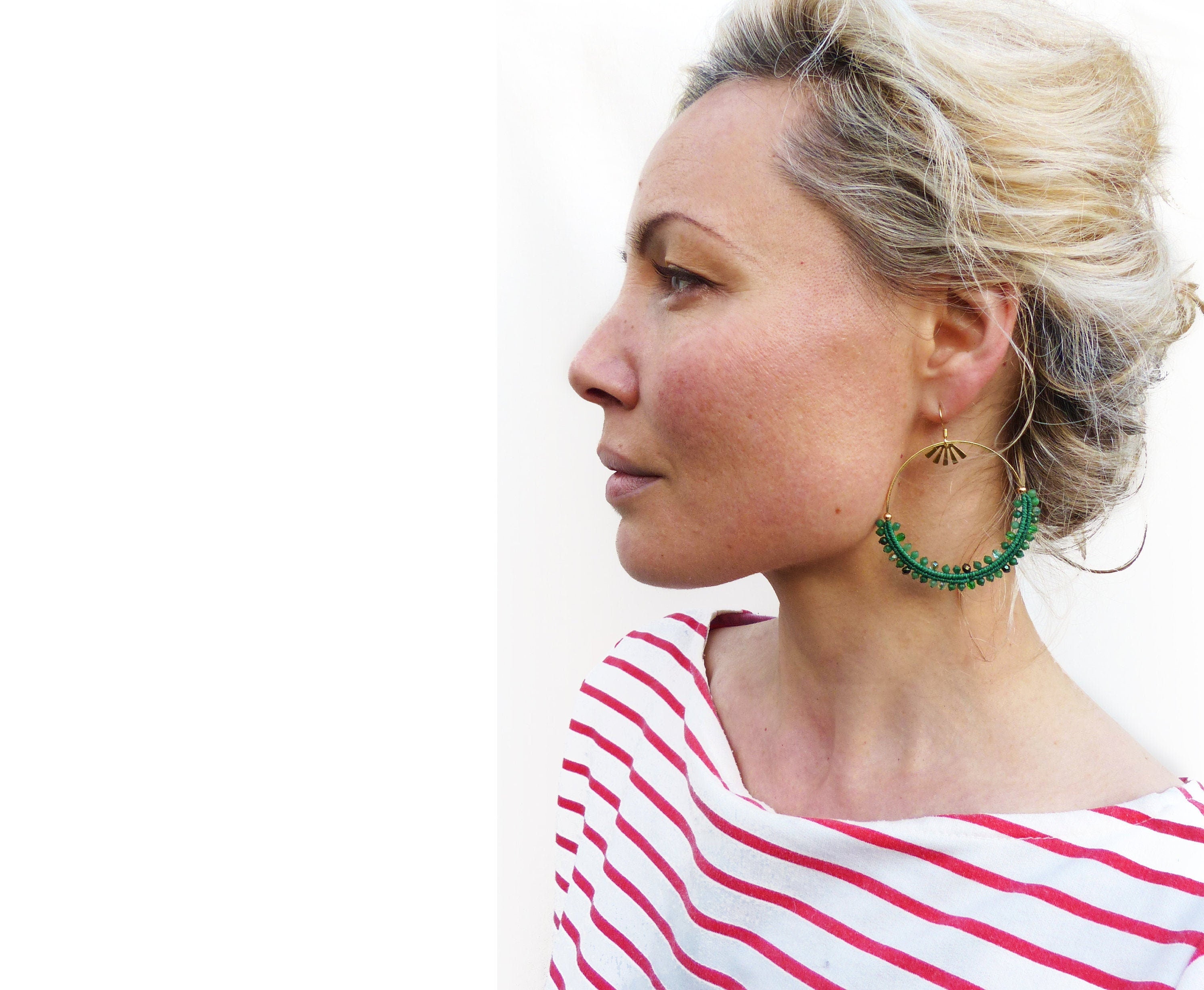 Peut inclure: Une femme portant une chemise rayée rouge et blanche avec de grandes boucles d'oreilles en or et vert. Les boucles d'oreilles sont faites de petites perles vertes et ont un charme en forme d'éventail doré.