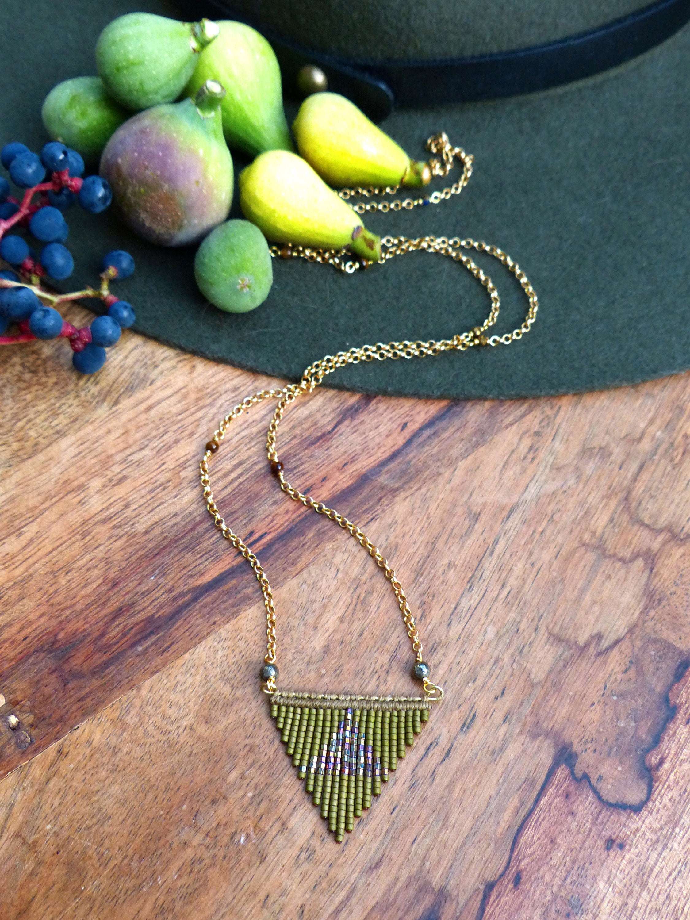 Peut inclure: Un collier de perles vertes avec un pendentif triangulaire. Le pendentif est fait de petites perles vertes et a un léger éclat. Le collier est sur une chaîne dorée.