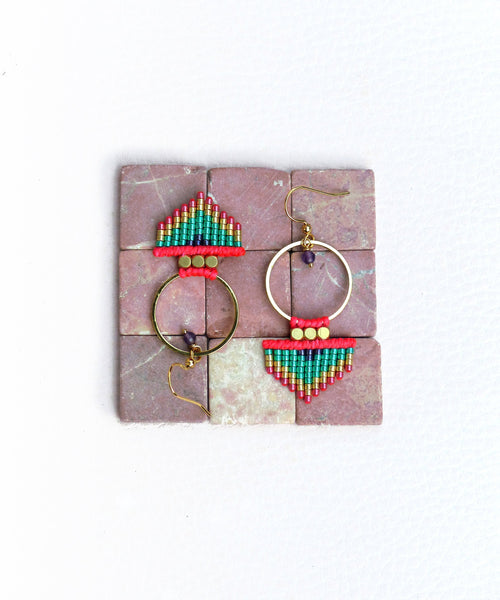 Peut inclure: Une paire de boucles d'oreilles créoles dorées avec des franges de perles rouges, vertes et dorées. La frange est en forme de triangle et comporte une petite perle violette en haut.