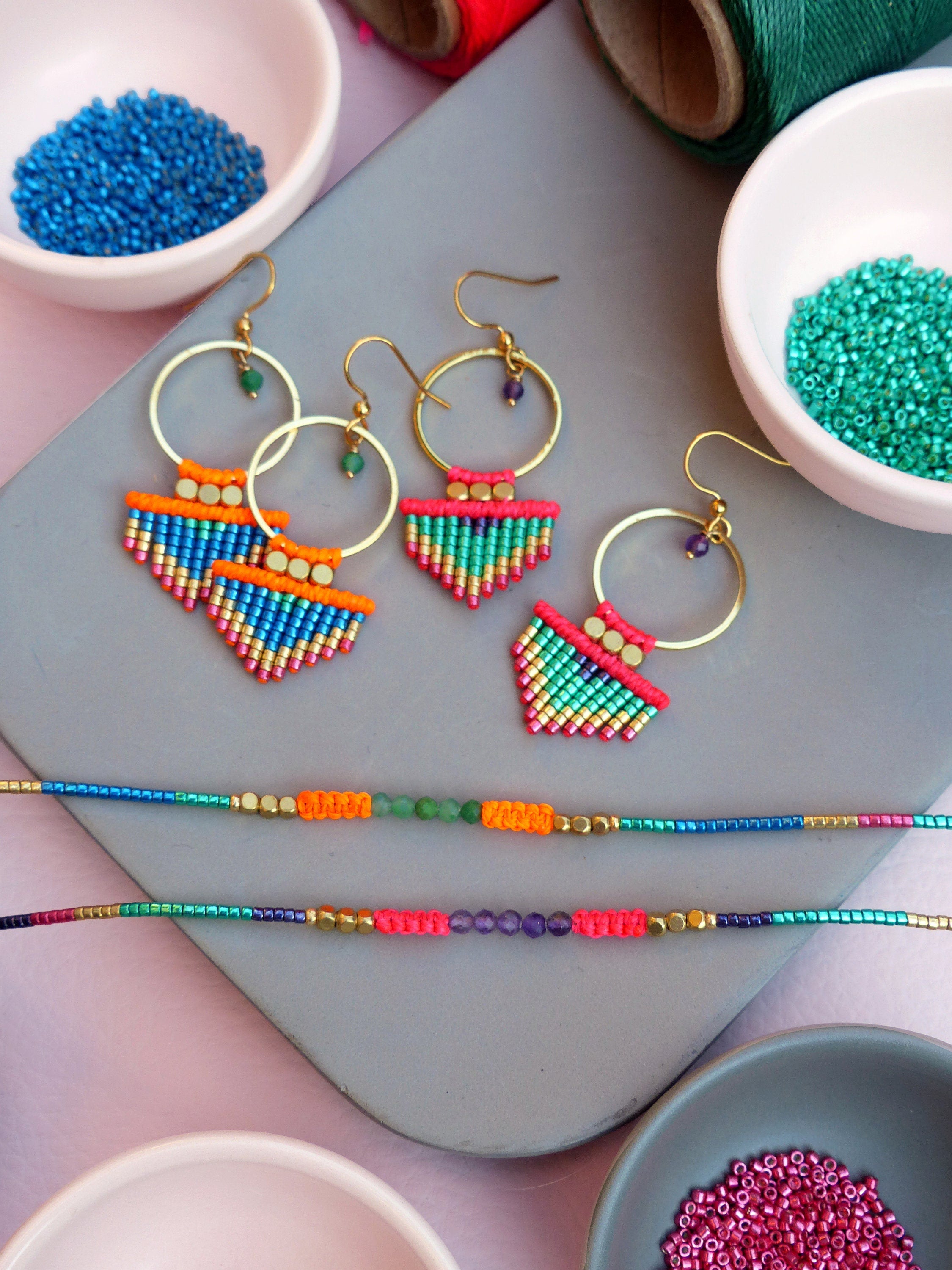 Peut inclure: Un ensemble de boucles d'oreilles en perles colorées et un bracelet en perles. Les boucles d'oreilles sont faites de petites perles colorées et ont un anneau en or. Le bracelet est fait de perles colorées variées, notamment turquoise, orange et rose.