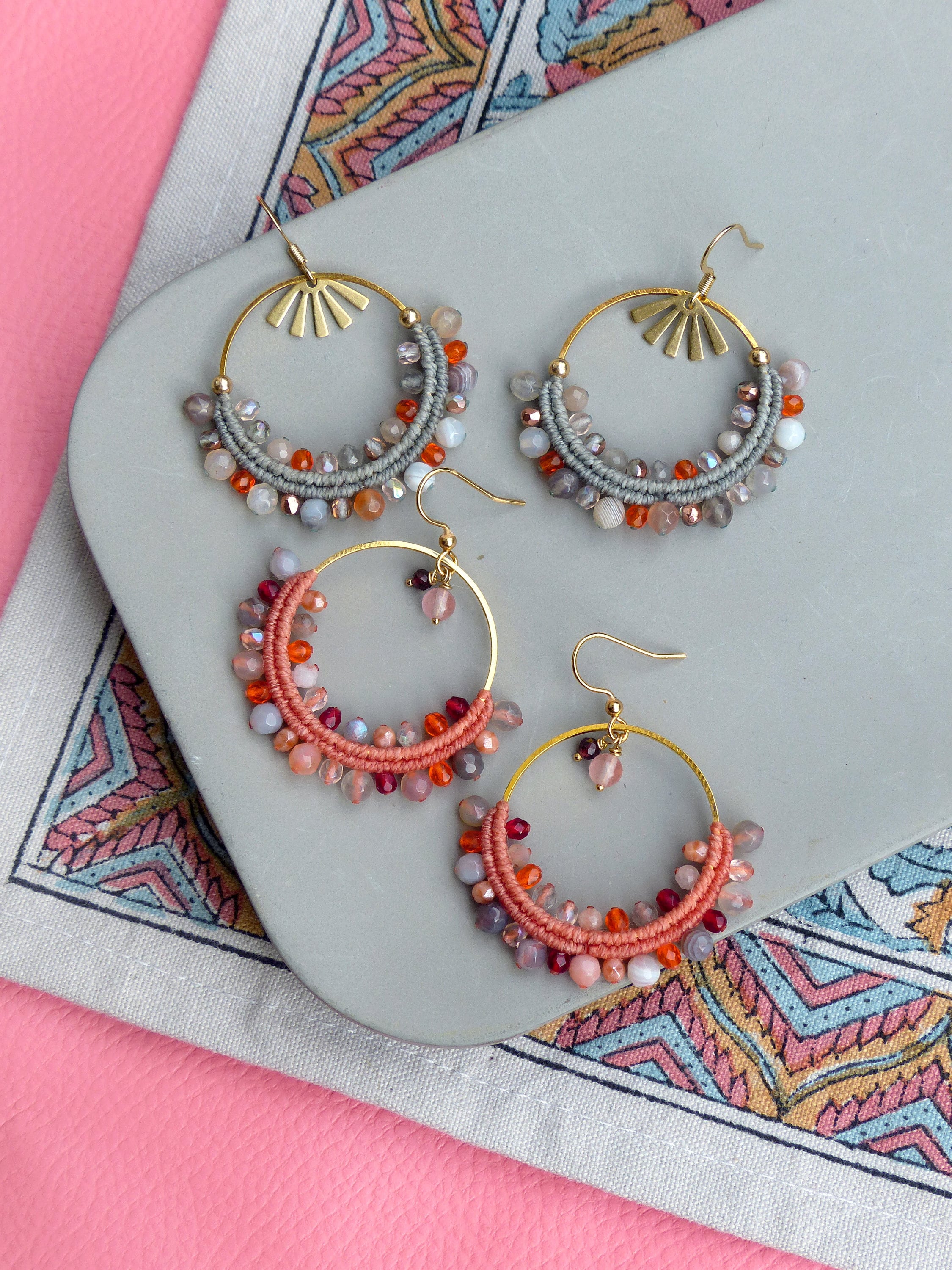 Peut inclure: Un ensemble de trois paires de boucles d'oreilles créoles avec un cadre en fil d'or et une variété de perles colorées. Les perles sont dans des tons d'orange, rouge, rose et gris.
