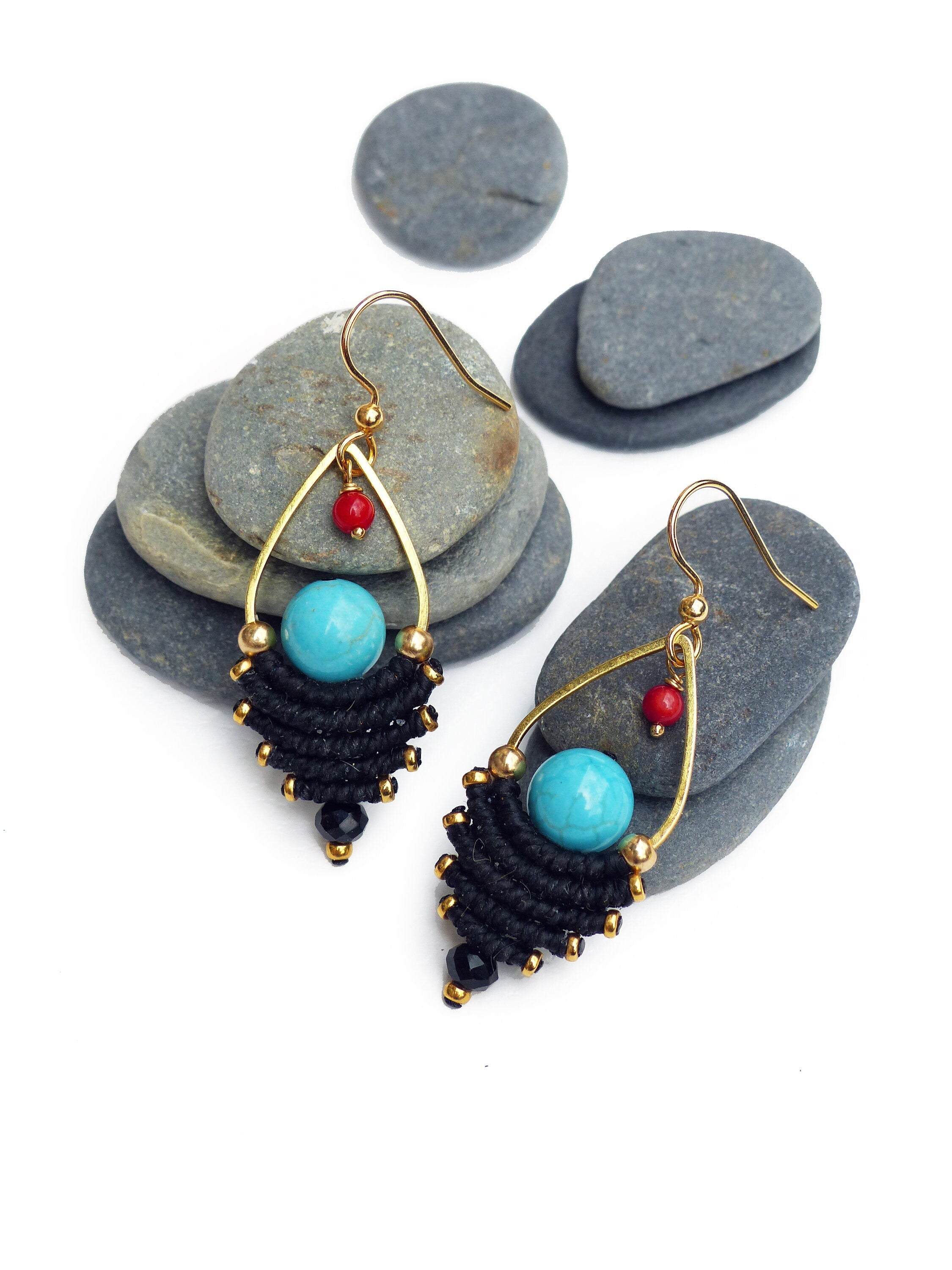 Peut inclure: Une paire de boucles d'oreilles pendantes turquoise et noires avec des accents dorés. Les boucles d'oreilles présentent une pierre turquoise, des perles noires et un fil d'or enveloppé de fil noir.