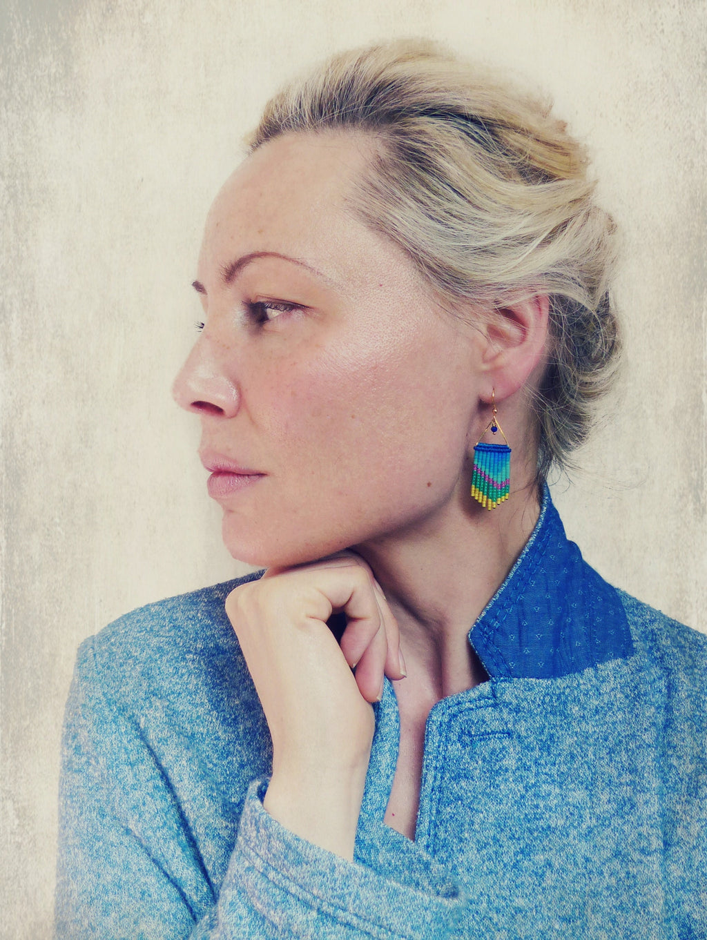 Peut inclure: Une femme aux cheveux blonds portant une veste en jean bleue et des boucles d'oreilles en perles bleues et jaunes. 
