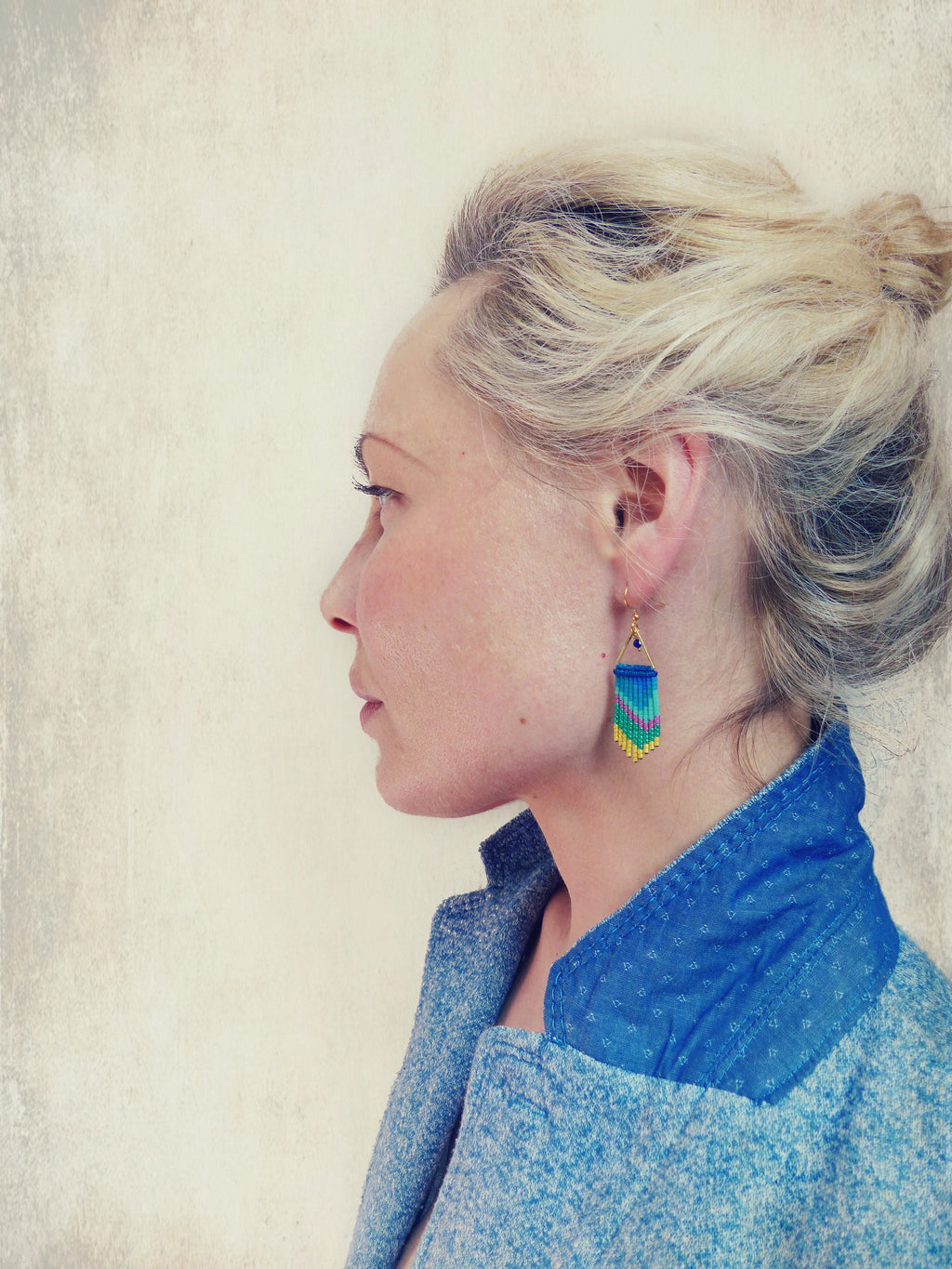 Peut inclure: Une femme aux cheveux blonds portant une veste en jean bleue et une paire de boucles d'oreilles pendantes turquoise et or.