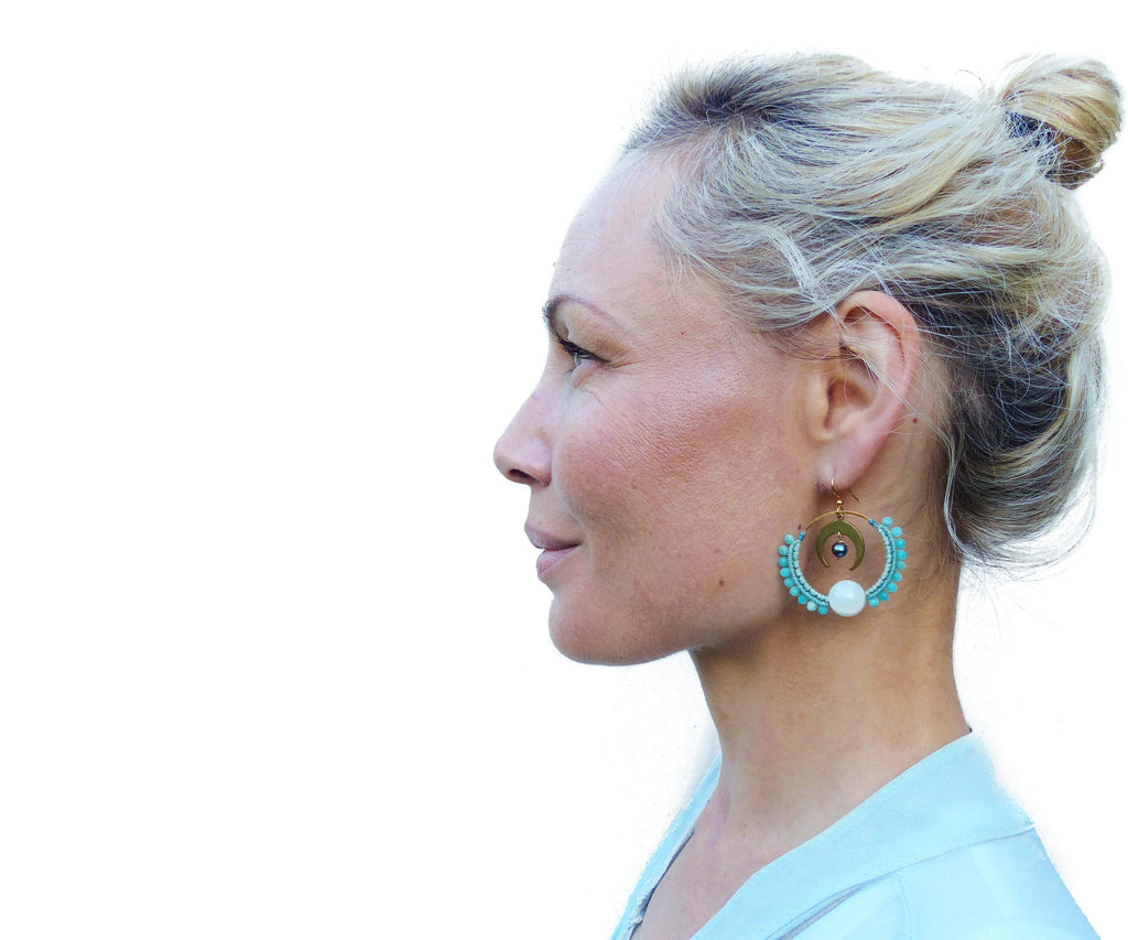 Peut inclure: Une femme aux cheveux blonds portant une paire de boucles d'oreilles créoles turquoise et or avec un accent de perle blanche.