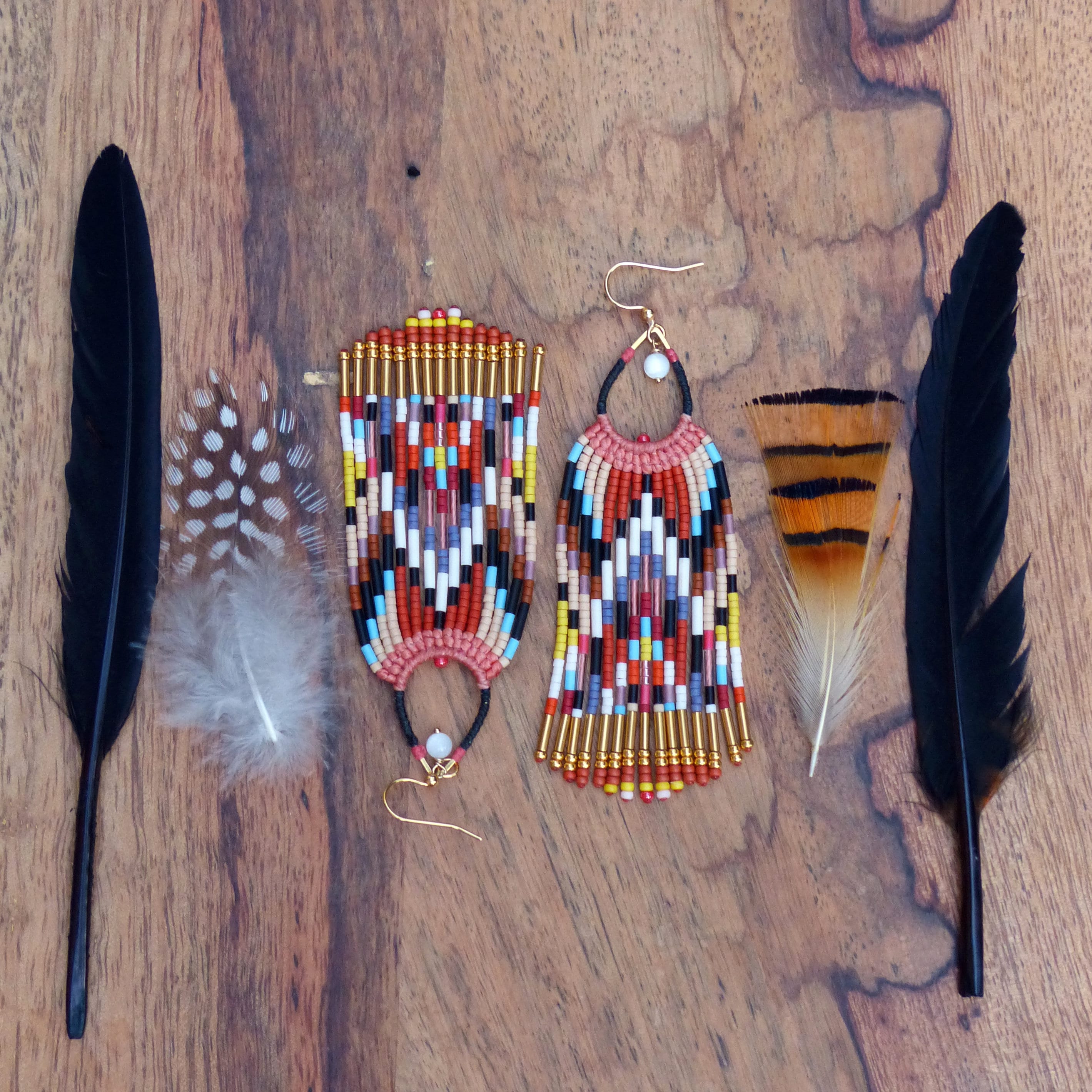 Peut inclure: Une paire de boucles d'oreilles en perles colorées avec un motif géométrique. Les boucles d'oreilles sont faites de petites perles colorées et d'accents dorés. 