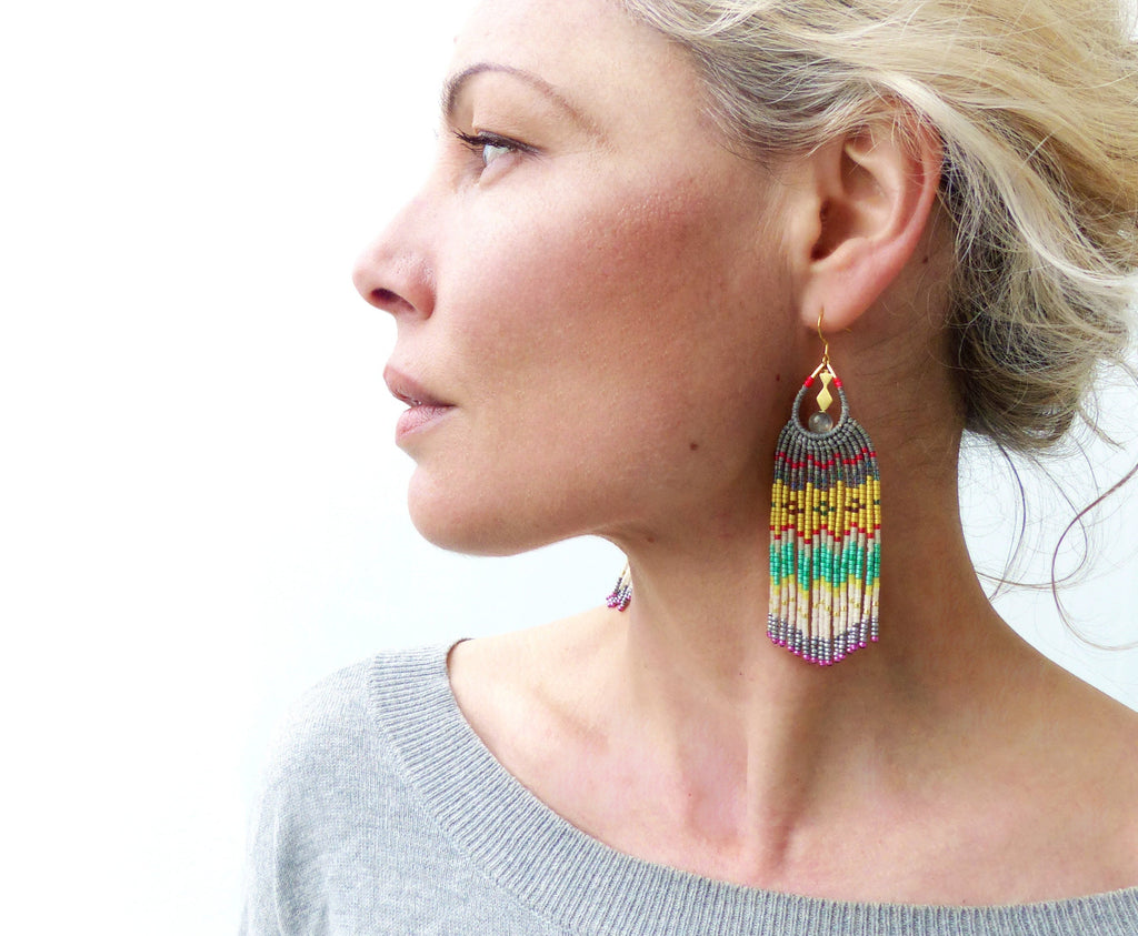Peut inclure: Une paire de longues boucles d'oreilles en perles colorées en forme de larme. Les boucles d'oreilles sont faites de perles grises, blanches, jaunes, vertes et rouges. Les boucles d'oreilles ont un crochet doré.