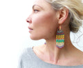 Peut inclure: Une paire de longues boucles d'oreilles en perles colorées en forme de larme. Les boucles d'oreilles sont faites de perles grises, blanches, jaunes, vertes et rouges. Les boucles d'oreilles ont un crochet doré.