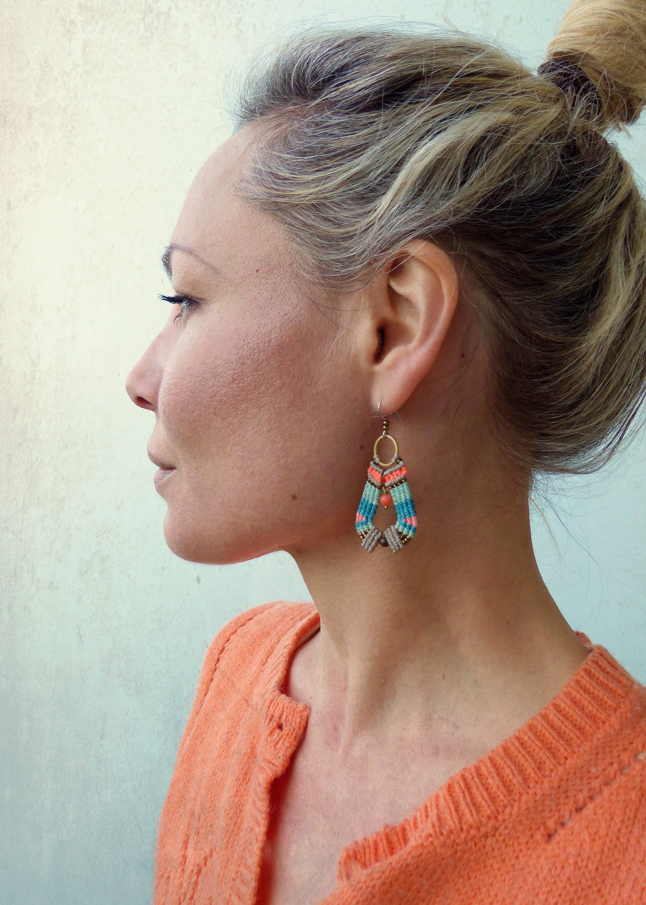 Peut inclure: Une paire de boucles d'oreilles pendantes avec un motif géométrique. Les boucles d'oreilles sont faites de fil coloré et ont une petite perle ronde au centre. Les boucles d'oreilles sont suspendues à un crochet doré.