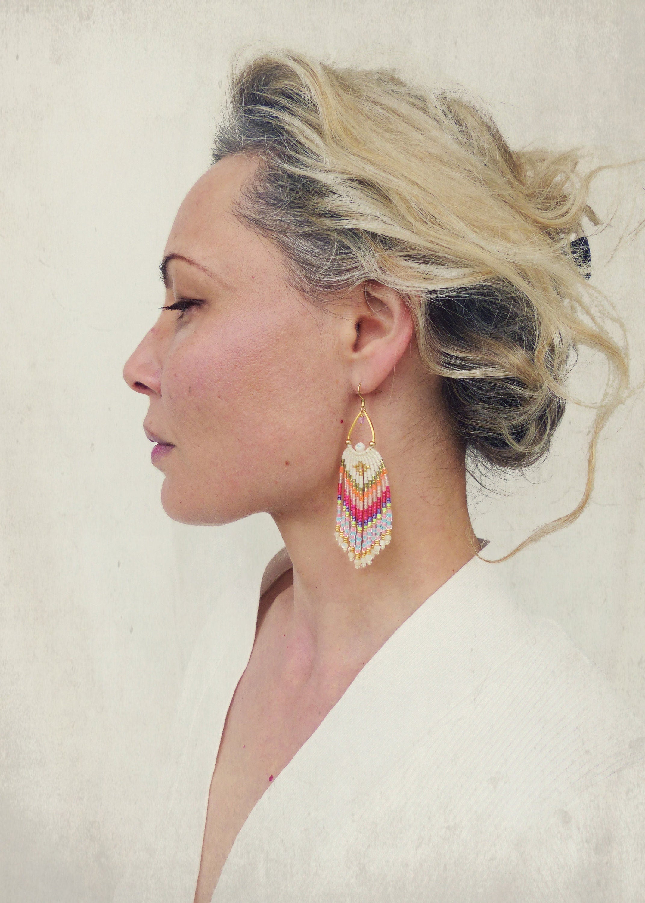 Peut inclure: Une paire de longues boucles d'oreilles en perles colorées avec un haut en forme de larme dorée. Les boucles d'oreilles sont faites avec une variété de couleurs, y compris le rose, le rouge, l'orange, le jaune, le blanc et le bleu.