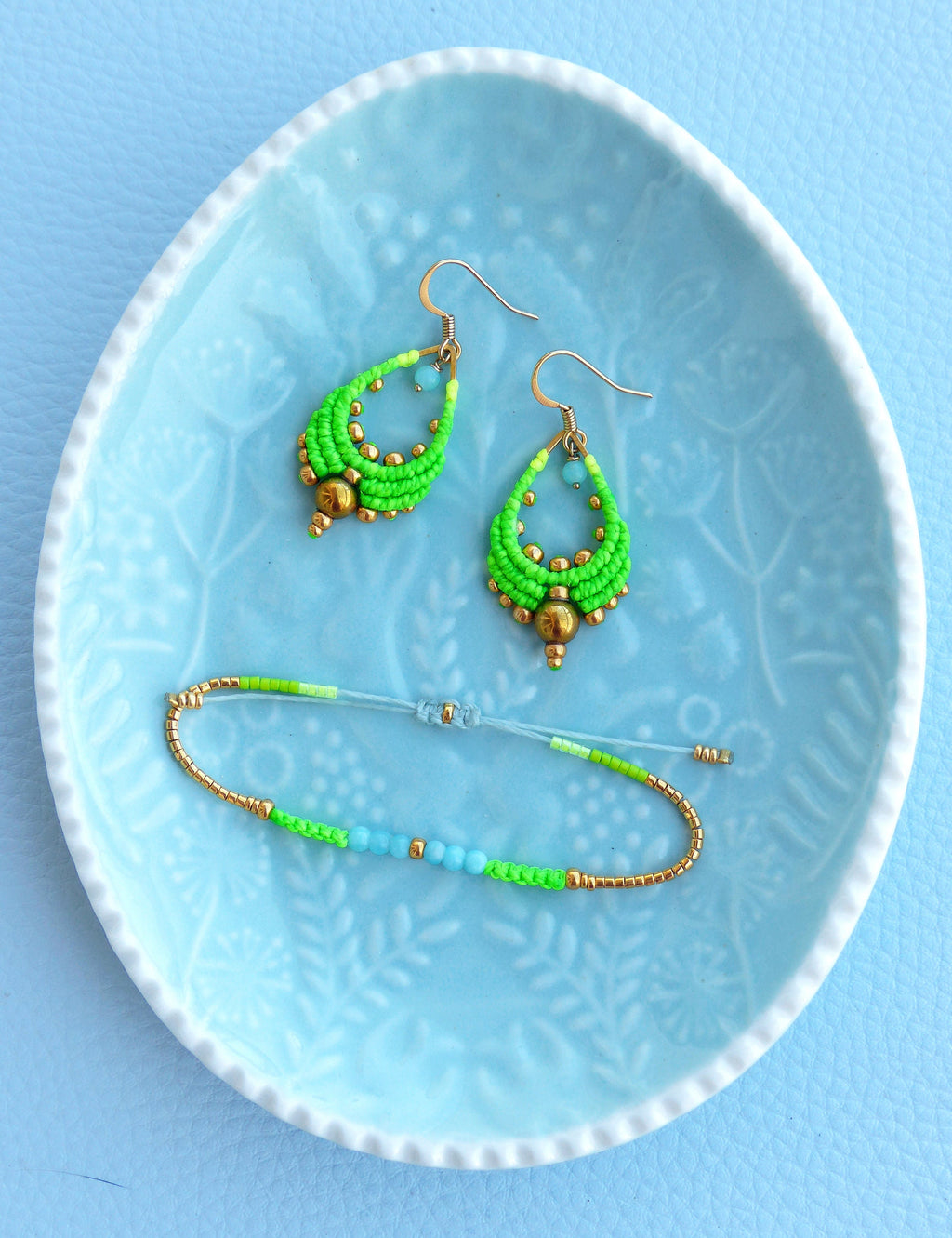 Peut inclure: Une paire de boucles d'oreilles en perles vertes et dorées et un bracelet assorti. Les boucles d'oreilles sont en forme de goutte et le bracelet est une simple bande.