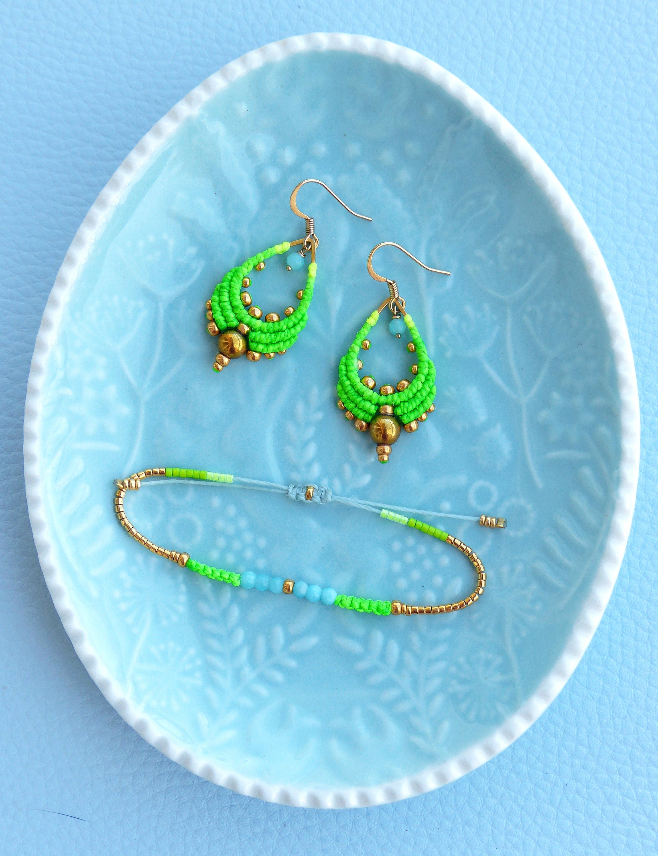 Peut inclure: Une paire de boucles d'oreilles en perles vertes et dorées et un bracelet assorti. Les boucles d'oreilles sont en forme de goutte et le bracelet est une simple bande.