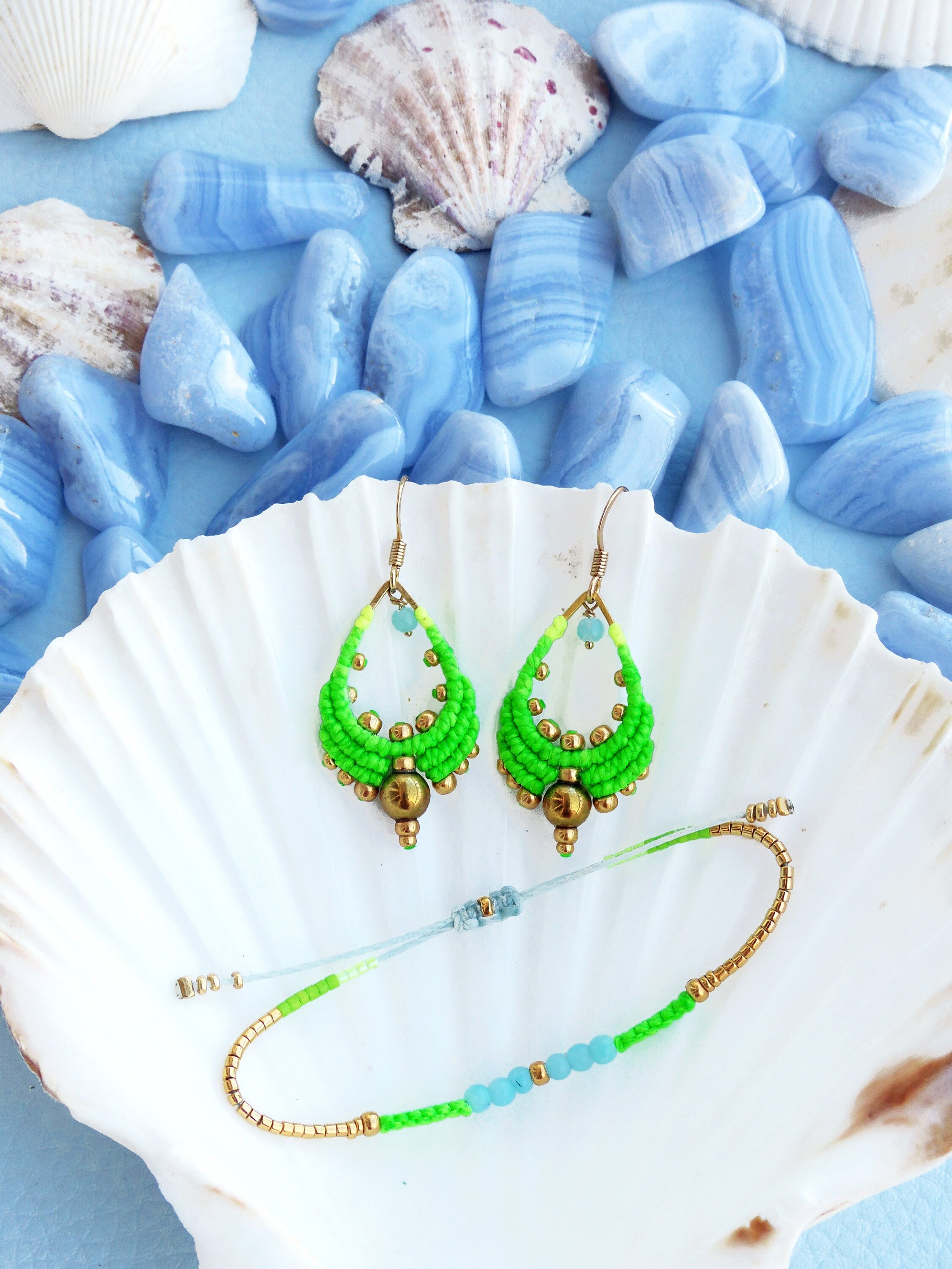 Peut inclure: Une paire de boucles d'oreilles en perles vertes et dorées et un bracelet assorti. Les boucles d'oreilles sont en forme de goutte et ont une perle dorée au bas. Le bracelet est un simple bracelet avec des perles vertes et bleues.