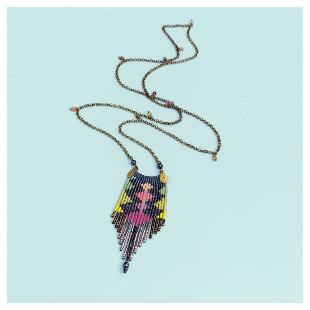 Peut inclure: Un collier long en chaîne dorée avec un pendentif en perles colorées. Le pendentif est un motif géométrique avec une frange de perles.