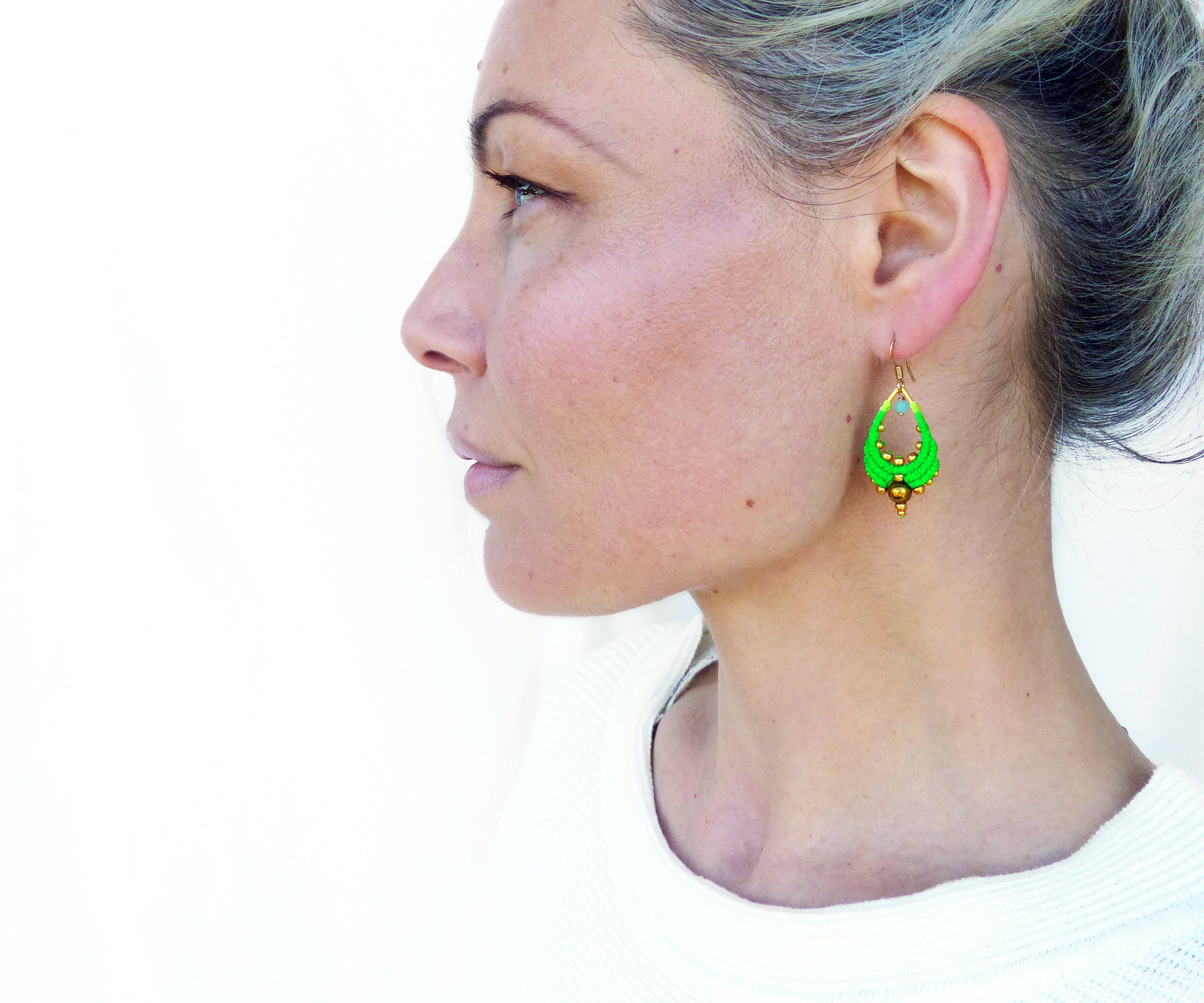 Peut inclure: Une paire de boucles d'oreilles pendantes vertes et dorées en forme de larme. Les boucles d'oreilles sont faites de petites perles et ont un accent doré en bas.