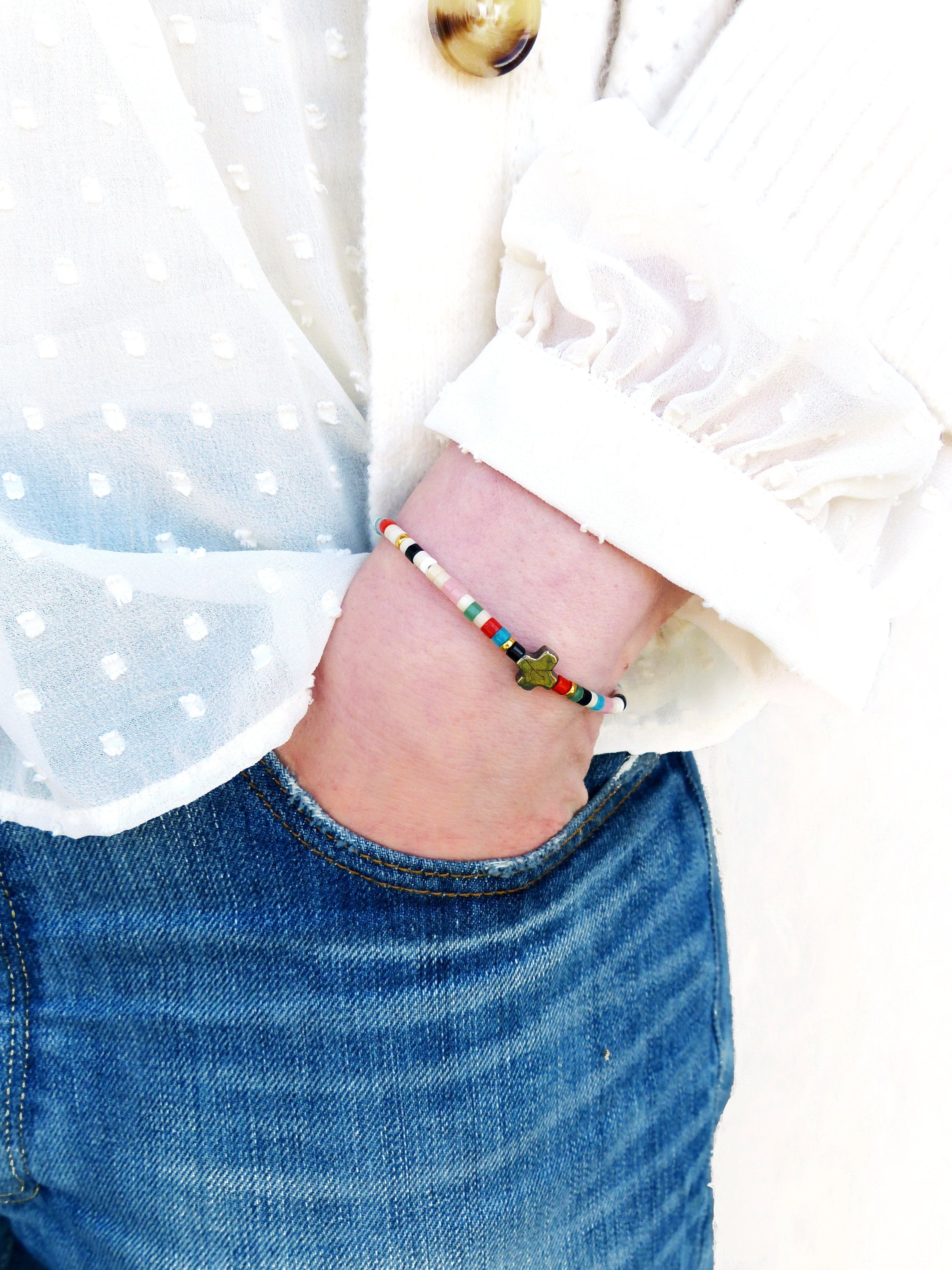 Peut inclure: Un bracelet en perles colorées avec un charme en forme d'étoile. Le bracelet est composé de petites perles rondes de différentes couleurs, notamment rouge, bleu, vert et blanc. Le charme en forme d'étoile est de couleur or et ajoute une touche d'éclat au bracelet.