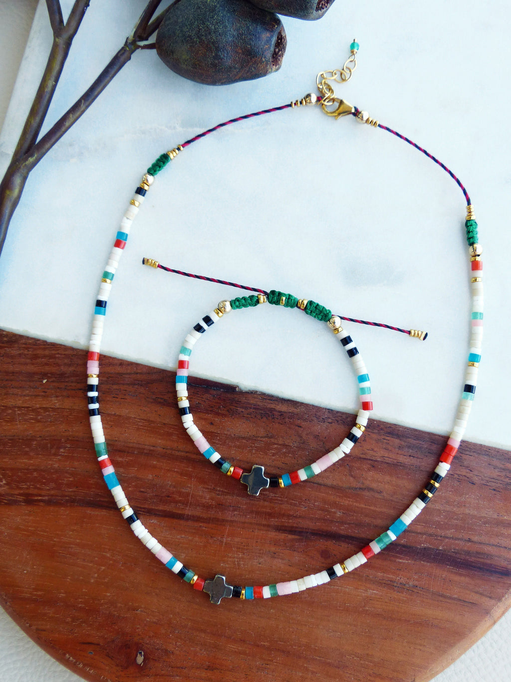 Peut inclure: Un ensemble de deux colliers de perles colorés avec des breloques en forme de croix argentées. Le collier est composé de perles blanches, noires, rouges, bleues et vertes. Le plus petit collier est un bracelet.