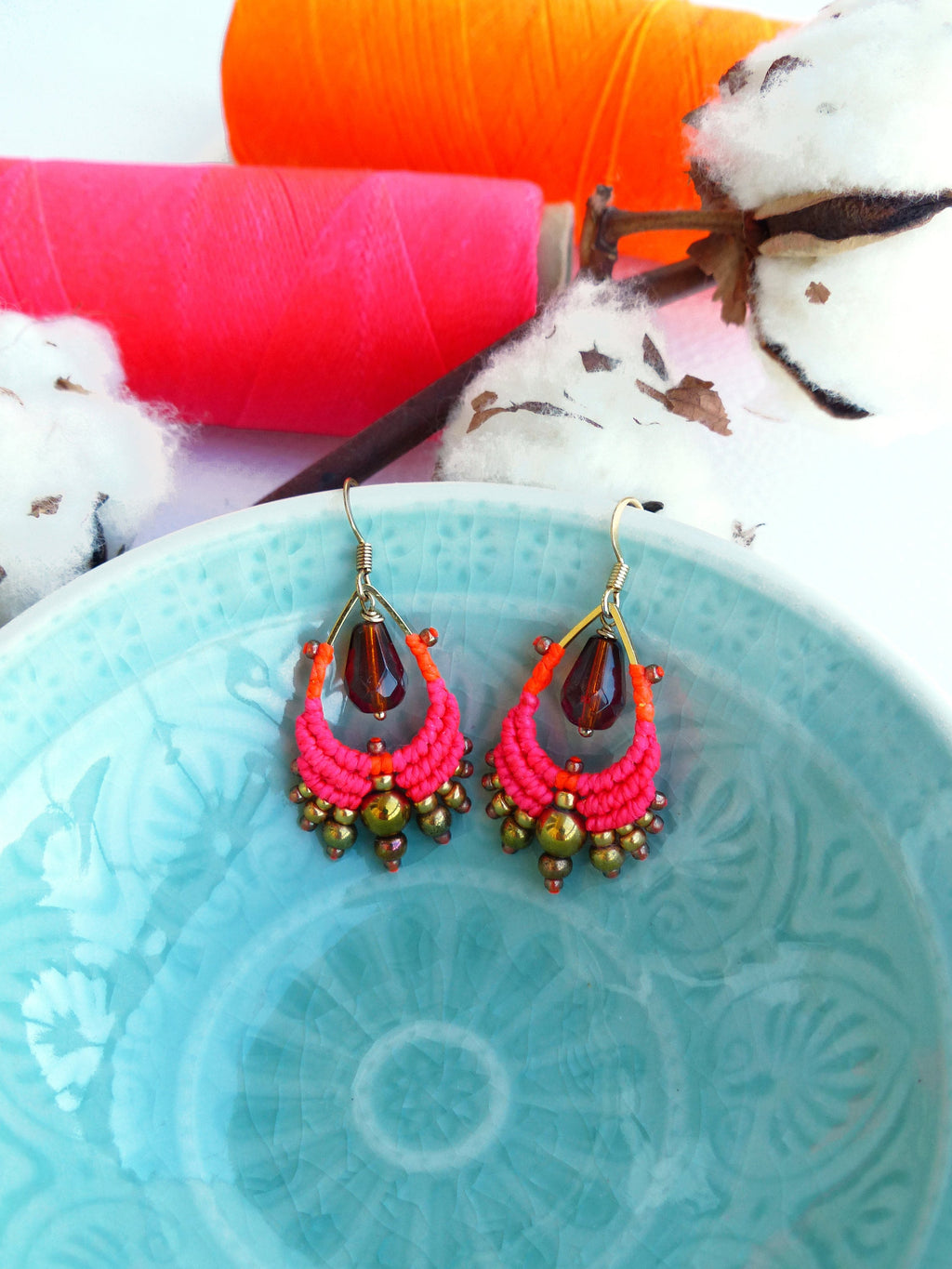 Peut inclure: Une paire de boucles d'oreilles en macramé rose et orange avec des perles brunes et des accents en verre en forme de larme.