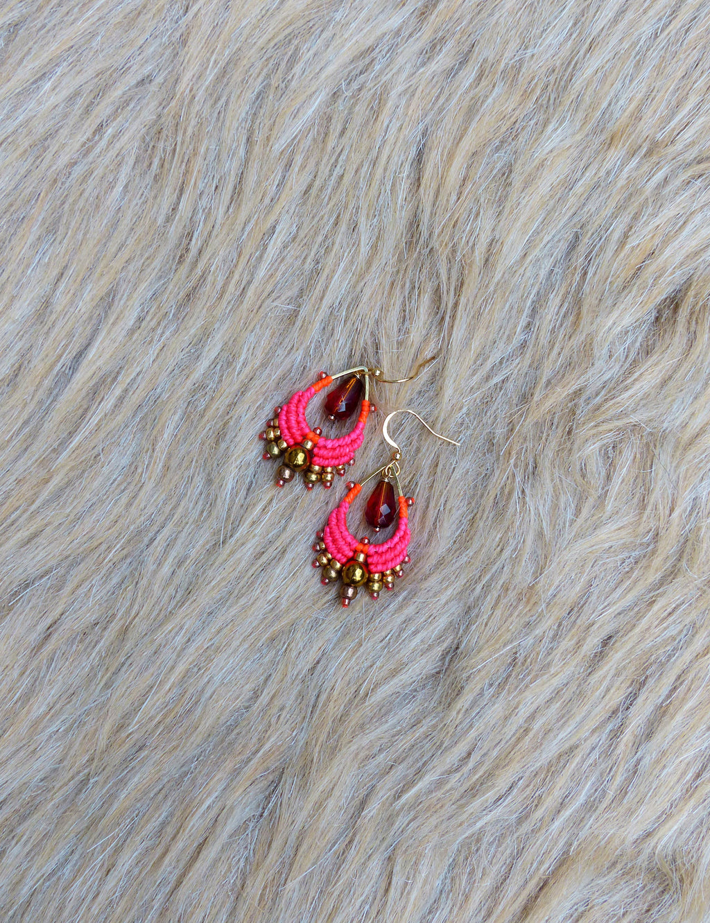 Peut inclure: Une paire de boucles d'oreilles en perles roses et dorées avec une perle de verre rouge en forme de larme au centre de chaque boucle d'oreille.