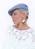 Peut inclure: Une femme portant un haut en crochet blanc et une casquette de newsboy en denim bleu. Elle porte de longues boucles d'oreilles en perles de couleur blanche, rouge et or.