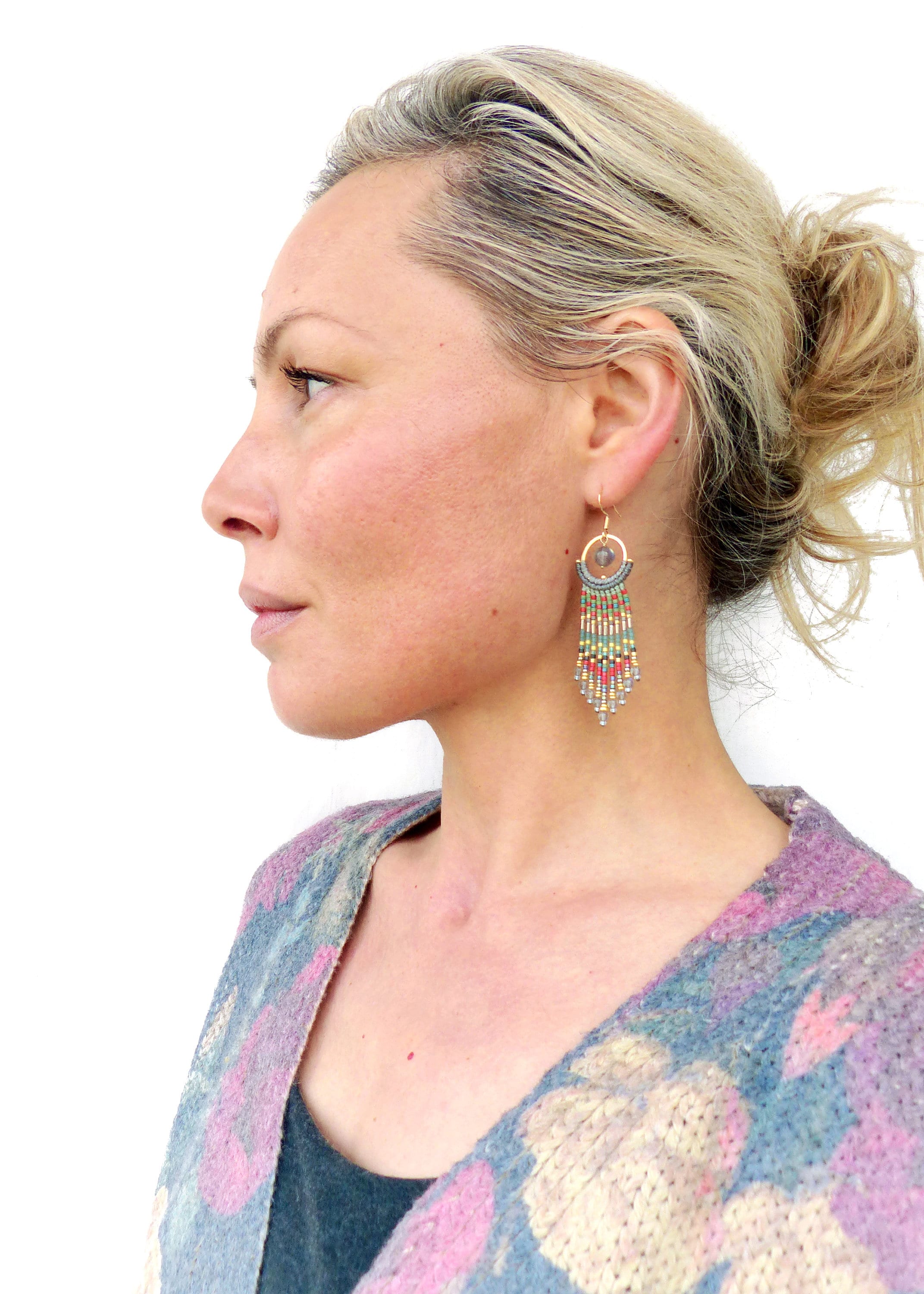 Peut inclure: Une femme portant un cardigan à motifs floraux avec de longues boucles d'oreilles en perles ornées d'une pierre ronde grise.