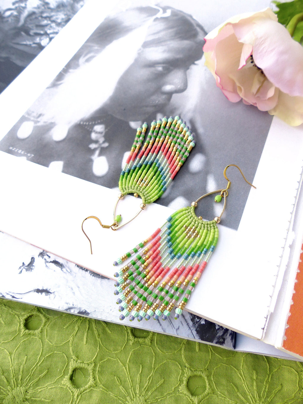 Peut inclure: Une paire de longues boucles d'oreilles en perles colorées avec des crochets dorés. Les boucles d'oreilles sont faites de perles vertes, roses et bleues et ont un design en forme de frange.
