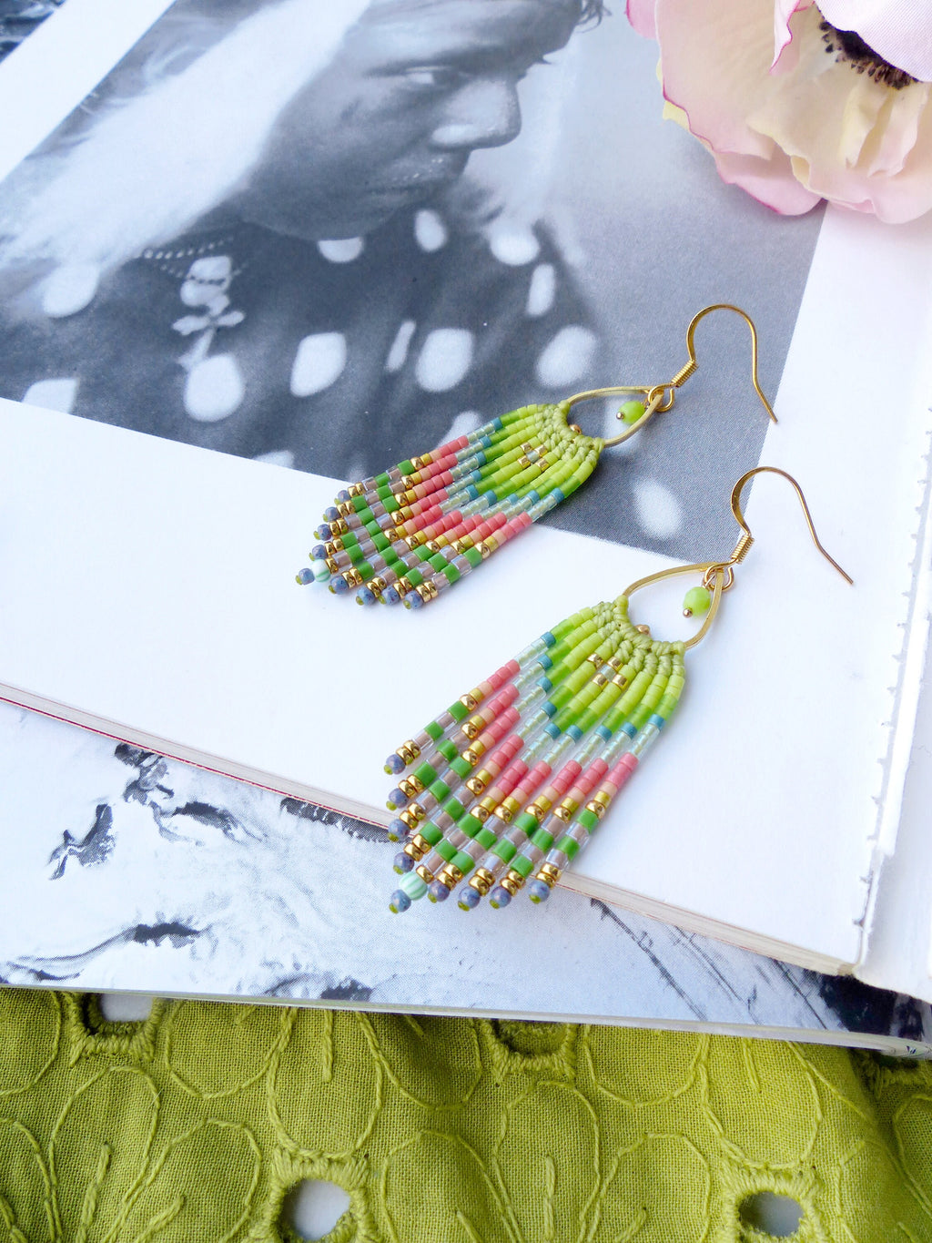 Peut inclure: Une paire de boucles d'oreilles pendantes en perles vertes, roses et bleues avec des crochets dorés. Les boucles d'oreilles sont faites de petites perles de rocaille et ont un design en forme de frange.