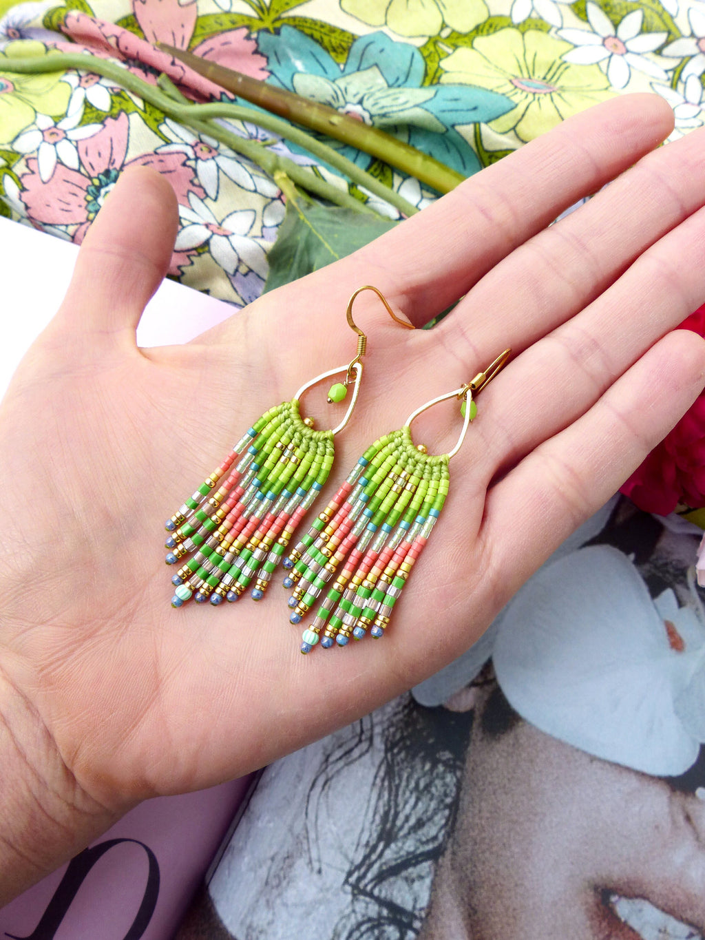 Peut inclure: Une paire de longues boucles d'oreilles pendantes en perles avec un crochet doré. Les boucles d'oreilles sont faites avec une variété de couleurs, y compris le vert, le rose et l'argent.