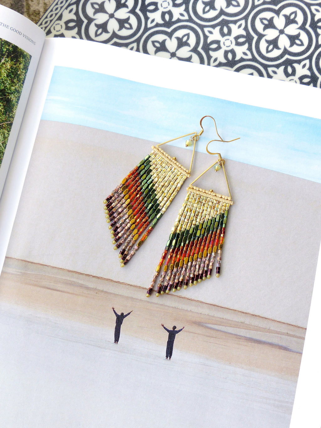 Peut inclure: Une paire de longues boucles d'oreilles en perles avec un motif triangle doré. Les boucles d'oreilles sont faites avec une variété de couleurs, y compris le beige, le brun, le vert, l'orange et le rouge.
