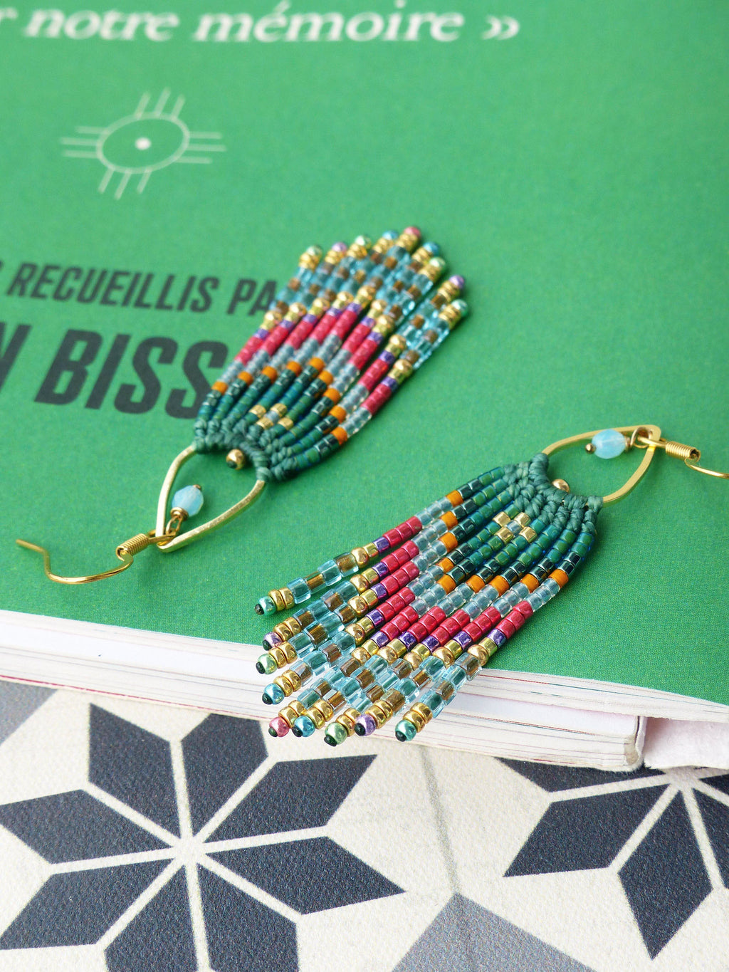 Peut inclure: Une paire de longues boucles d'oreilles en perles avec un motif turquoise, vert et or. Les boucles d'oreilles sont faites de petites perles colorées et ont un design en forme de glands.