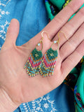 Peut inclure: Une paire de boucles d'oreilles pendantes en perles vertes, bleues et roses avec des crochets dorés et une perle transparente en haut.