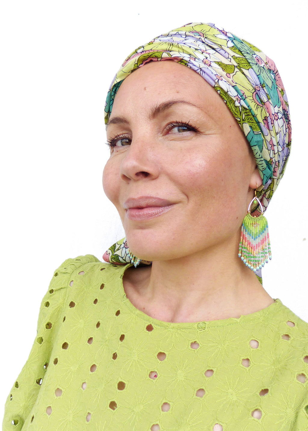 Peut inclure: Une femme aux cheveux courts porte un foulard floral vert et des boucles d'oreilles en perles vertes. Elle porte une blouse à manches courtes en dentelle vert clair.