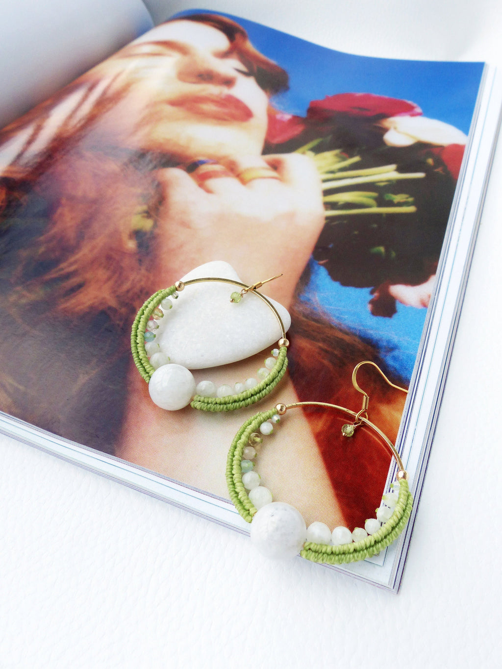 Peut inclure: Une paire de boucles d'oreilles créoles vertes et blanches avec une grosse perle blanche sur chaque créole. Les boucles d'oreilles sont faites de fil vert et de petites perles blanches.