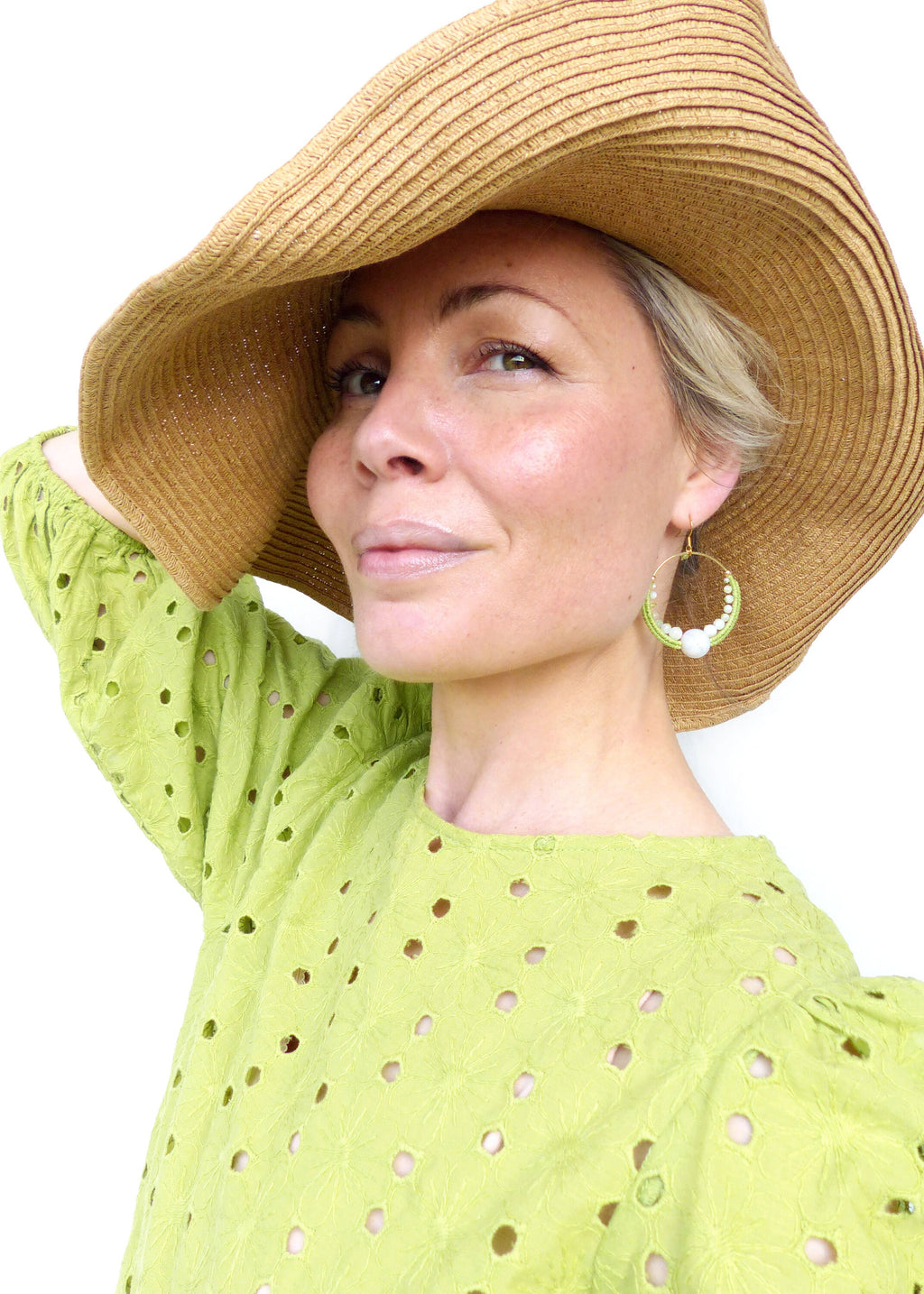 Peut inclure: Une femme portant un chapeau de paille et une blouse verte à œillets avec des boucles d'oreilles en perles blanches et en perles vertes.