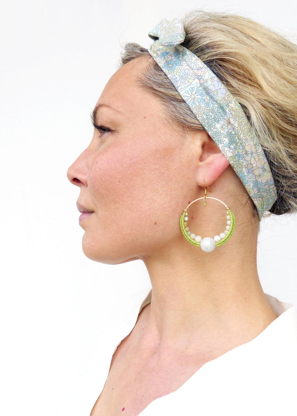 Peut inclure: Une femme portant un bandeau floral et de grandes boucles d'oreilles en forme de cerceau avec des perles vertes et blanches et une grosse perle blanche. 