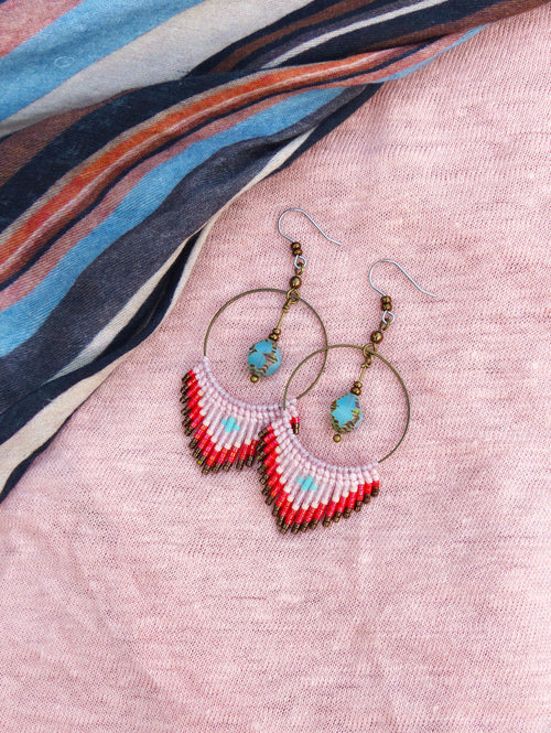 Peut inclure: Une paire de boucles d'oreilles créoles avec une frange de perles. La frange est composée de perles roses, rouges et bleues. Les créoles sont argentées et les perles sont enfilées sur un fil.