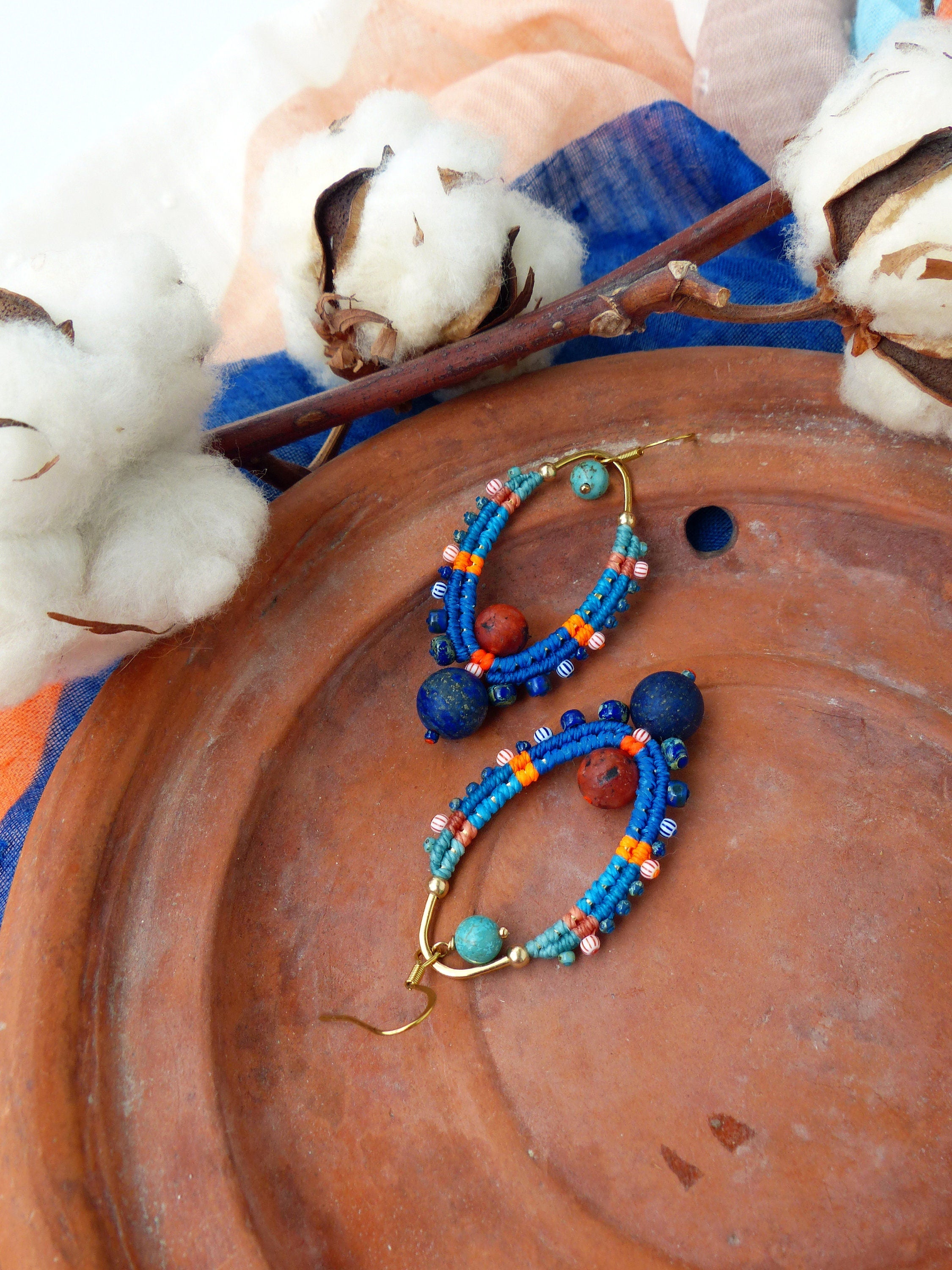 Peut inclure: Une paire de boucles d'oreilles faites à la main avec des perles bleues, orange et turquoise. Les boucles d'oreilles sont faites avec un fil d'or et ont une forme de larme.